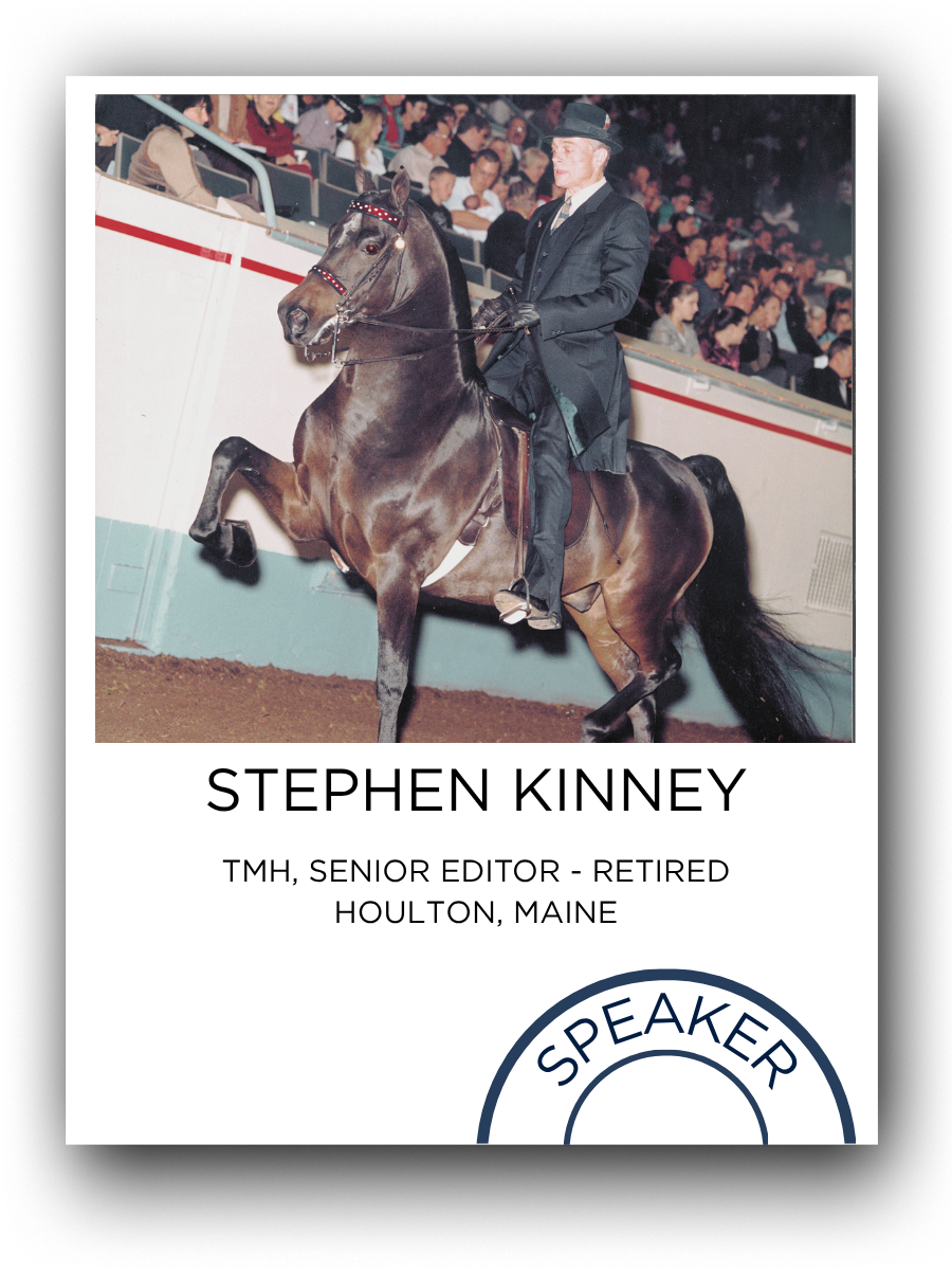 Man in a dark suit and hat riding a rearing horse in an arena with audience seats filled with spectators in the background.