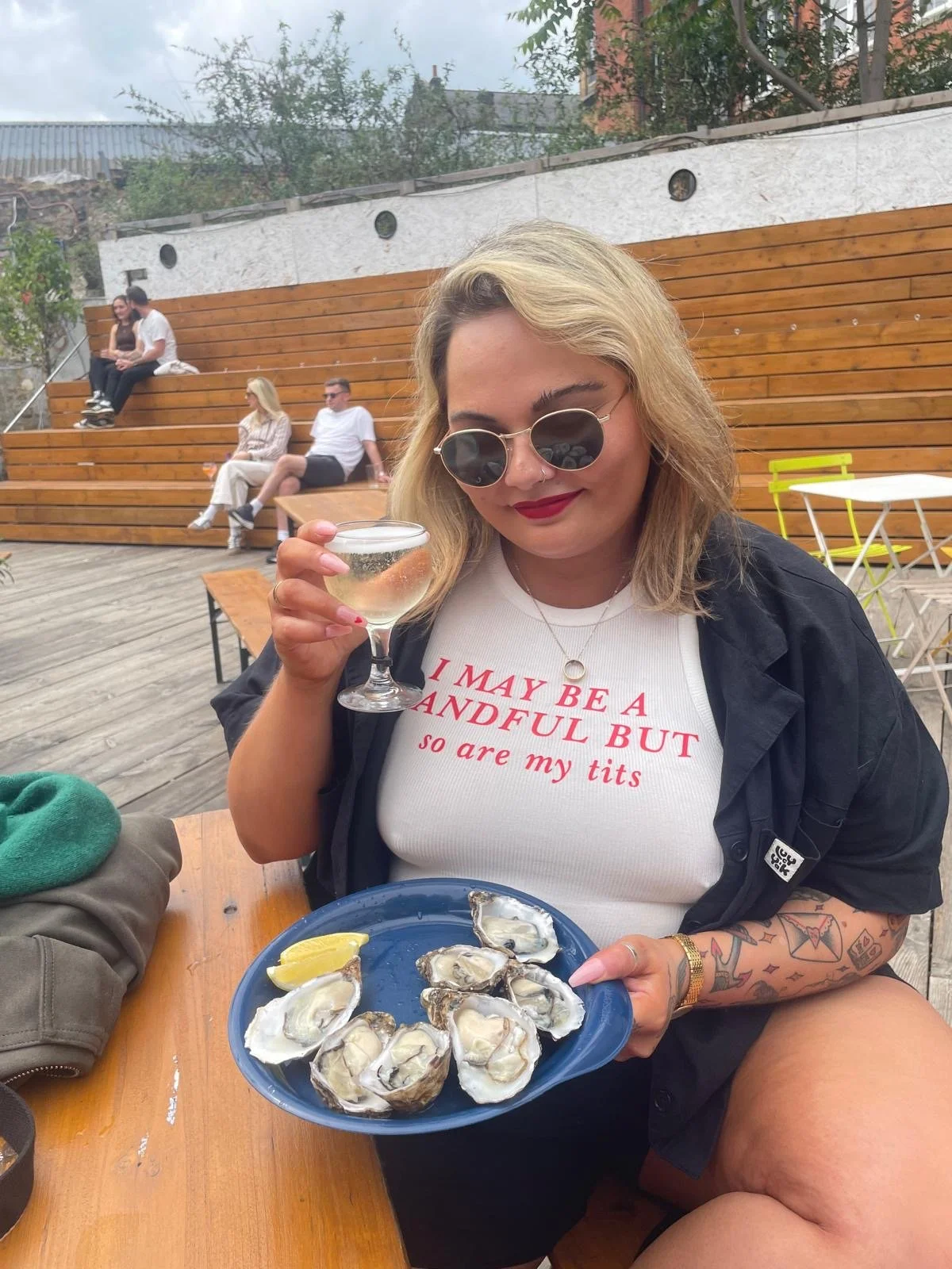 A picture of Soraya Nair holding a glass of champagne and a plate of oysters