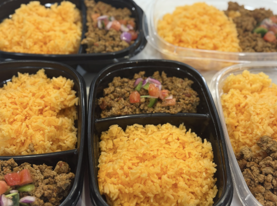 Multiple meal prep containers with ground beef, seasoned rice, and diced vegetables