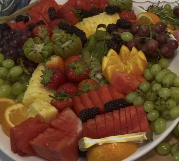 A platter of assorted fresh fruits including watermelon, strawberries, grapes, pineapple, kiwi, blackberries, and orange slices, catered by Nikee Catering.
