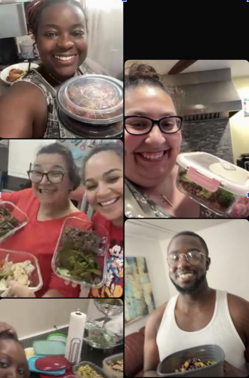 A group of diverse people at a gathering, smiling and holding containers of food, with some in a kitchen setting.