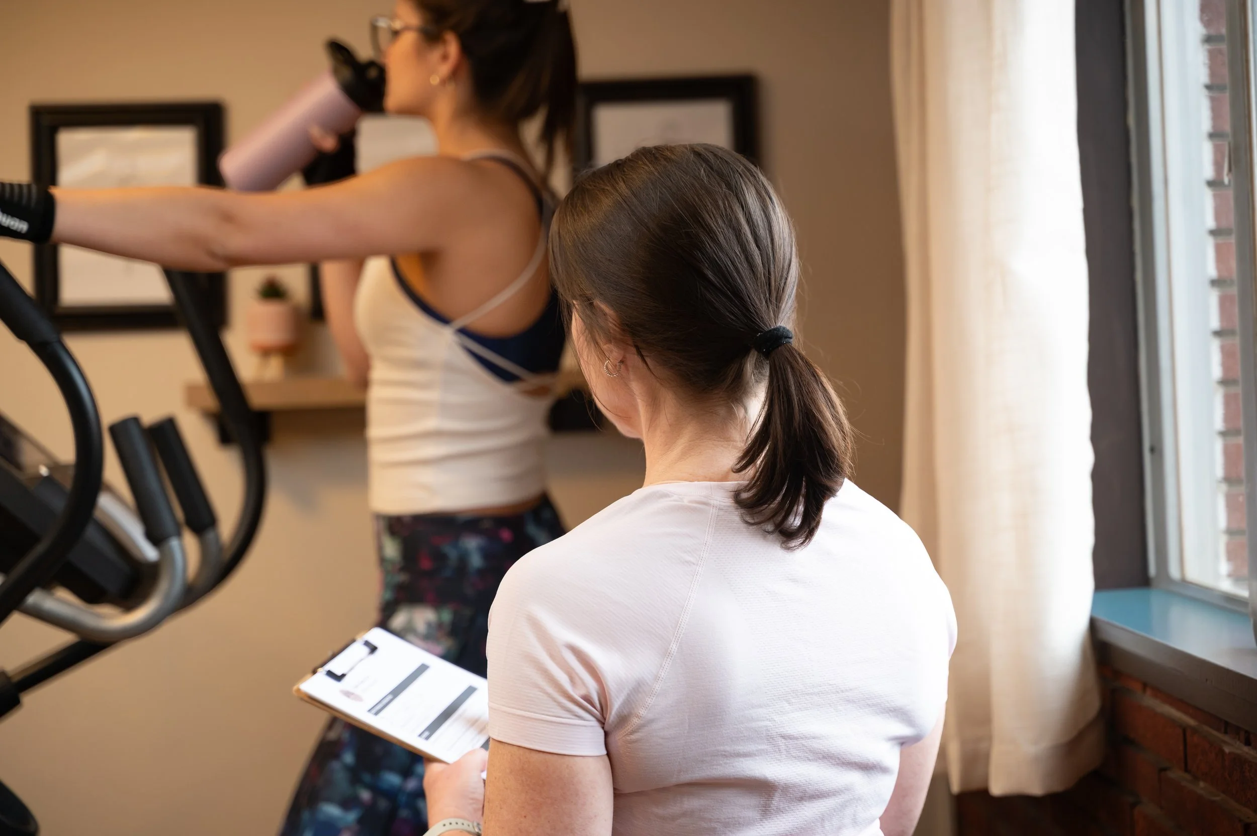 Two women sitting at a table looking at a laptop screen showing furniture products.