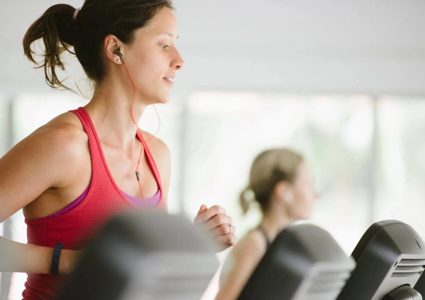 A group of people participating in a fitness class, smiling and looking at the camera, in a gym setting.