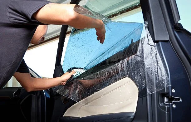 Person installing or replacing a windshield on a vehicle inside a garage.