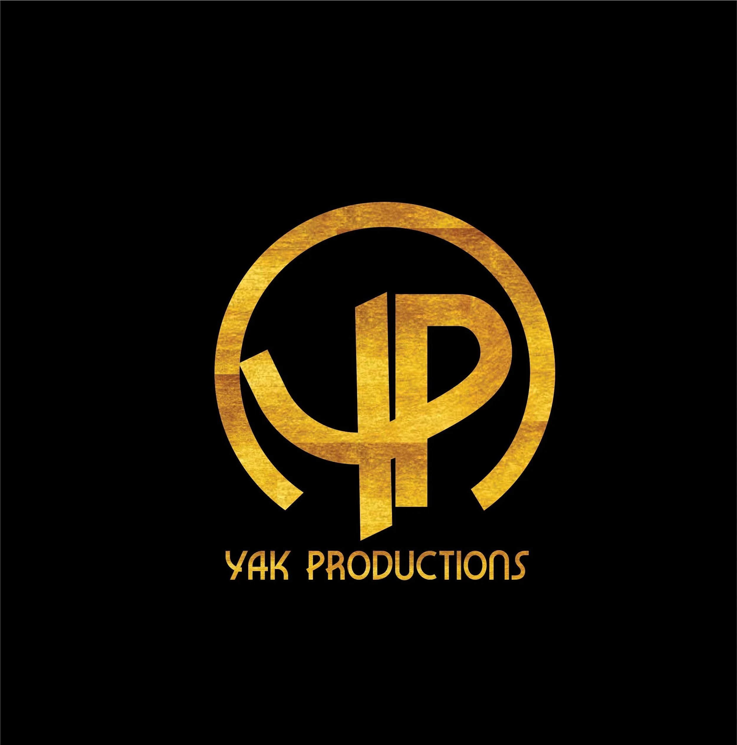 Gold and black logo for YAK PRODUCTIONS featuring a stylized circular emblem with a vertical line dividing two shapes, and the text "YAK PRODUCTIONS" below in gold.