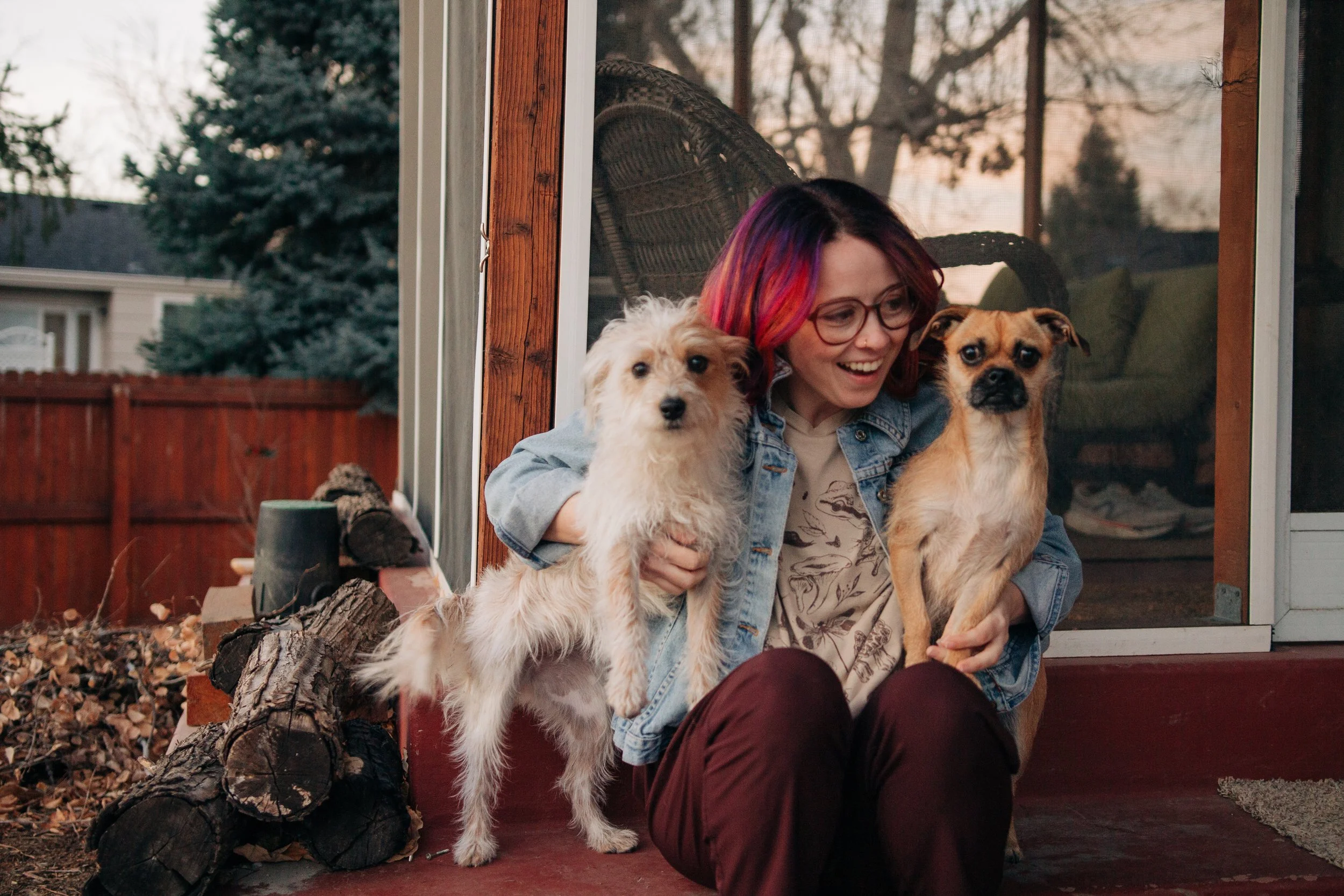 Becca Meyers sitting outside, smiling, with two small dogs on her lap