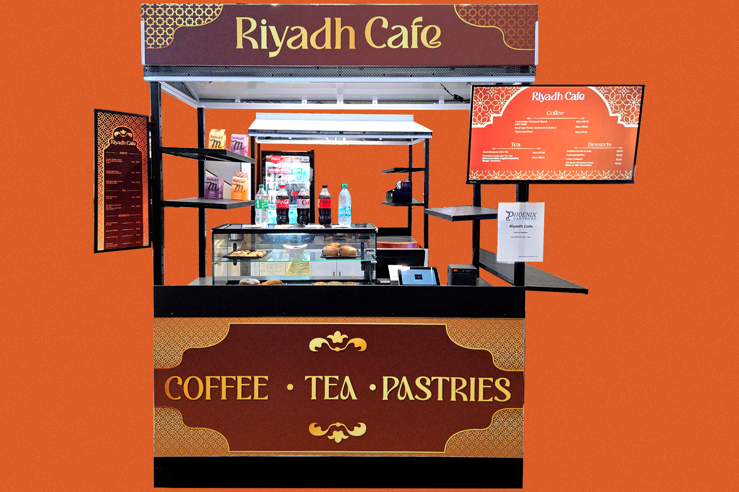 A food stand for Riyadh Cafe offering coffee, tea, and pastries, with a menu board and display case in front.