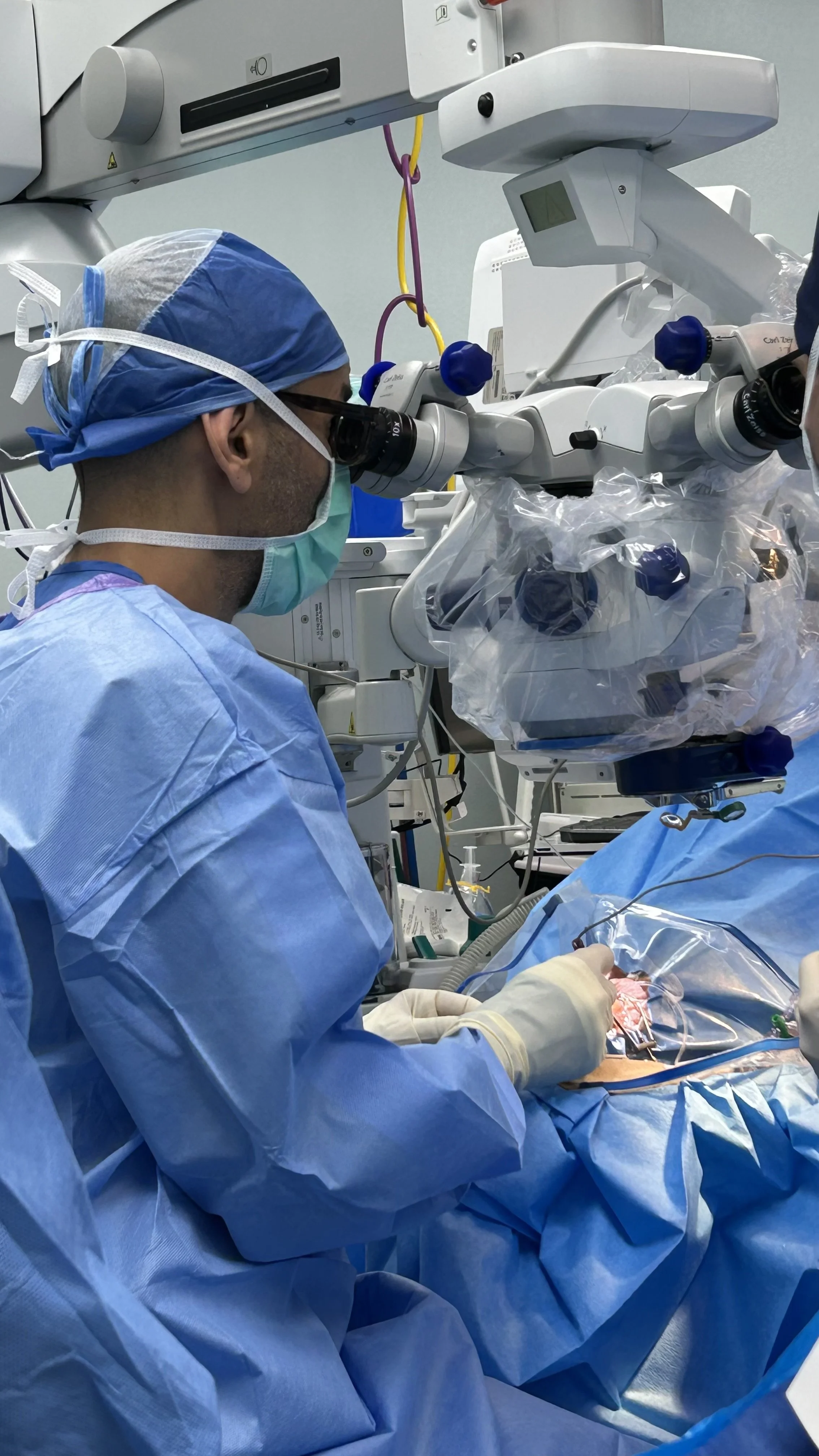 A surgeon operating in an operating room using a microscope for microsurgery.