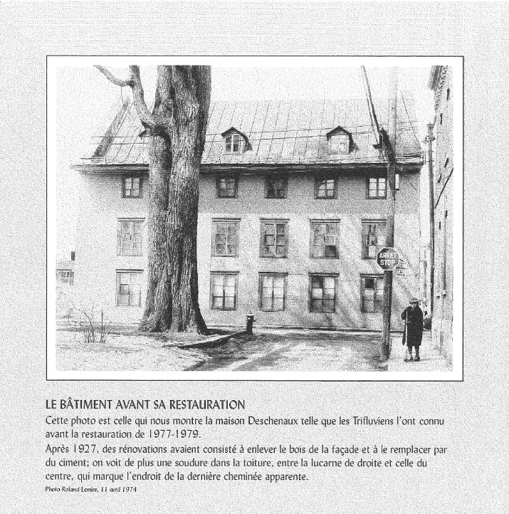 Une vieille maison en pierre avec un grand arbre devant, vue d'une rue, avec une femme et un homme au coin de la rue près d'un panneau "Arrêt".