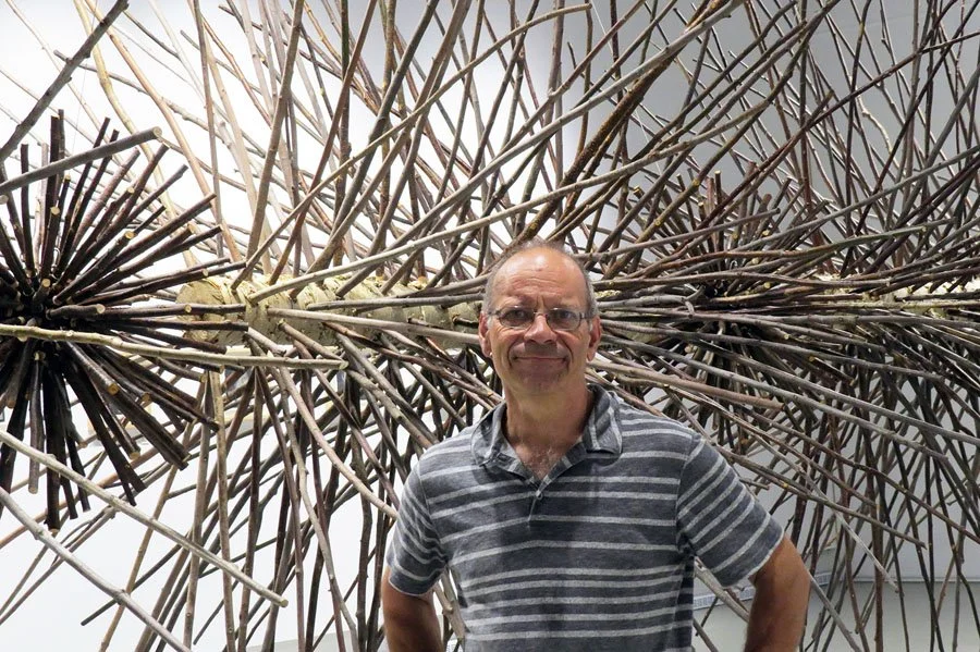 Photo de Roger Gaudreau devant une de ses sculptures