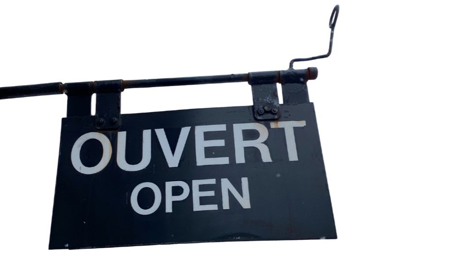 Un panneau suspendu indiquant que le lieu est ouvert, avec le texte "OUVERT" en français et "OPEN" en anglais sur un fond noir.