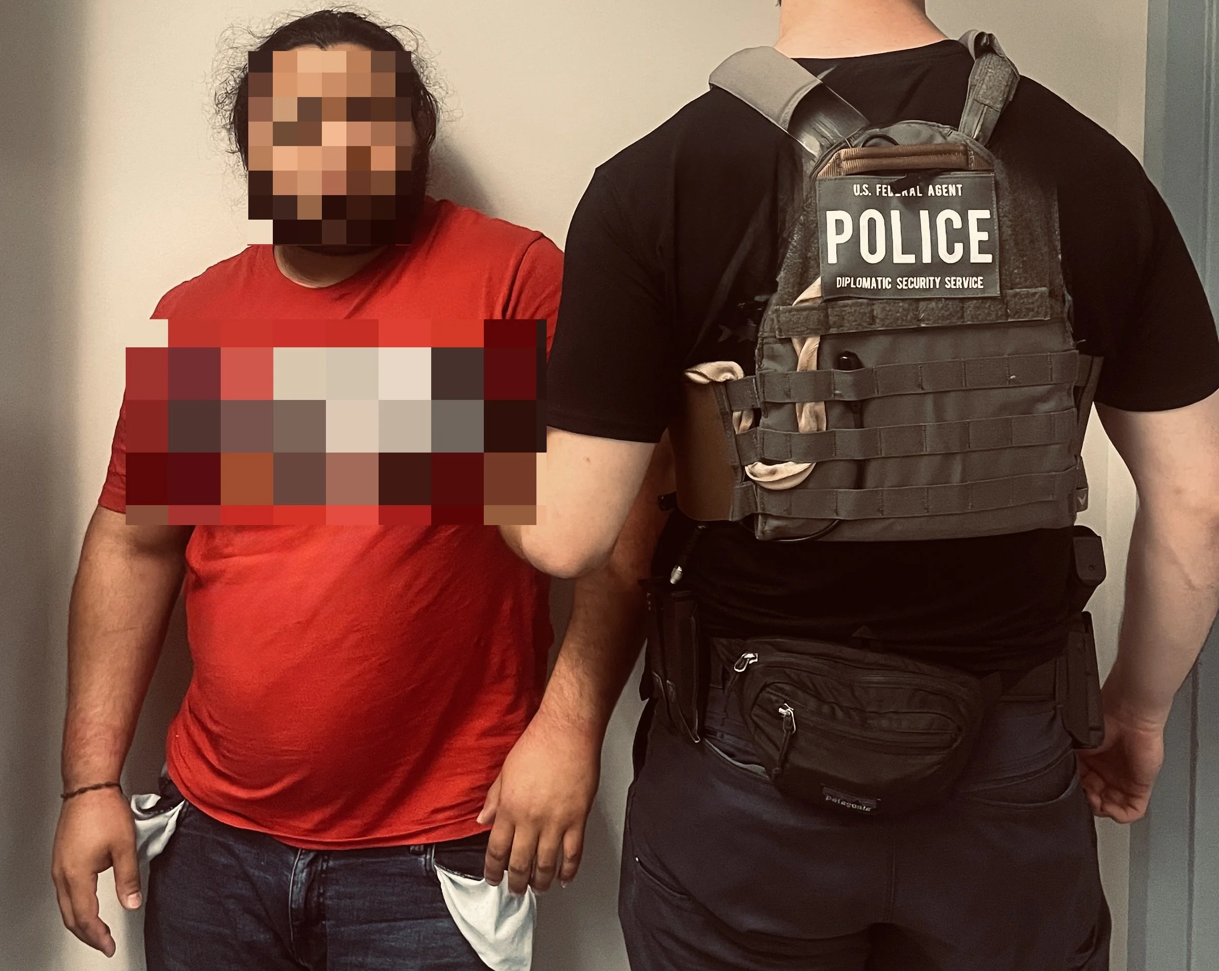 A man in a red T-shirt with pixelated face, standing with his hands by his sides, next to a police officer in tactical gear with his back facing the camera. The officer is wearing a vest labeled 'POLICE' and 'U.S. Federal Agent'.