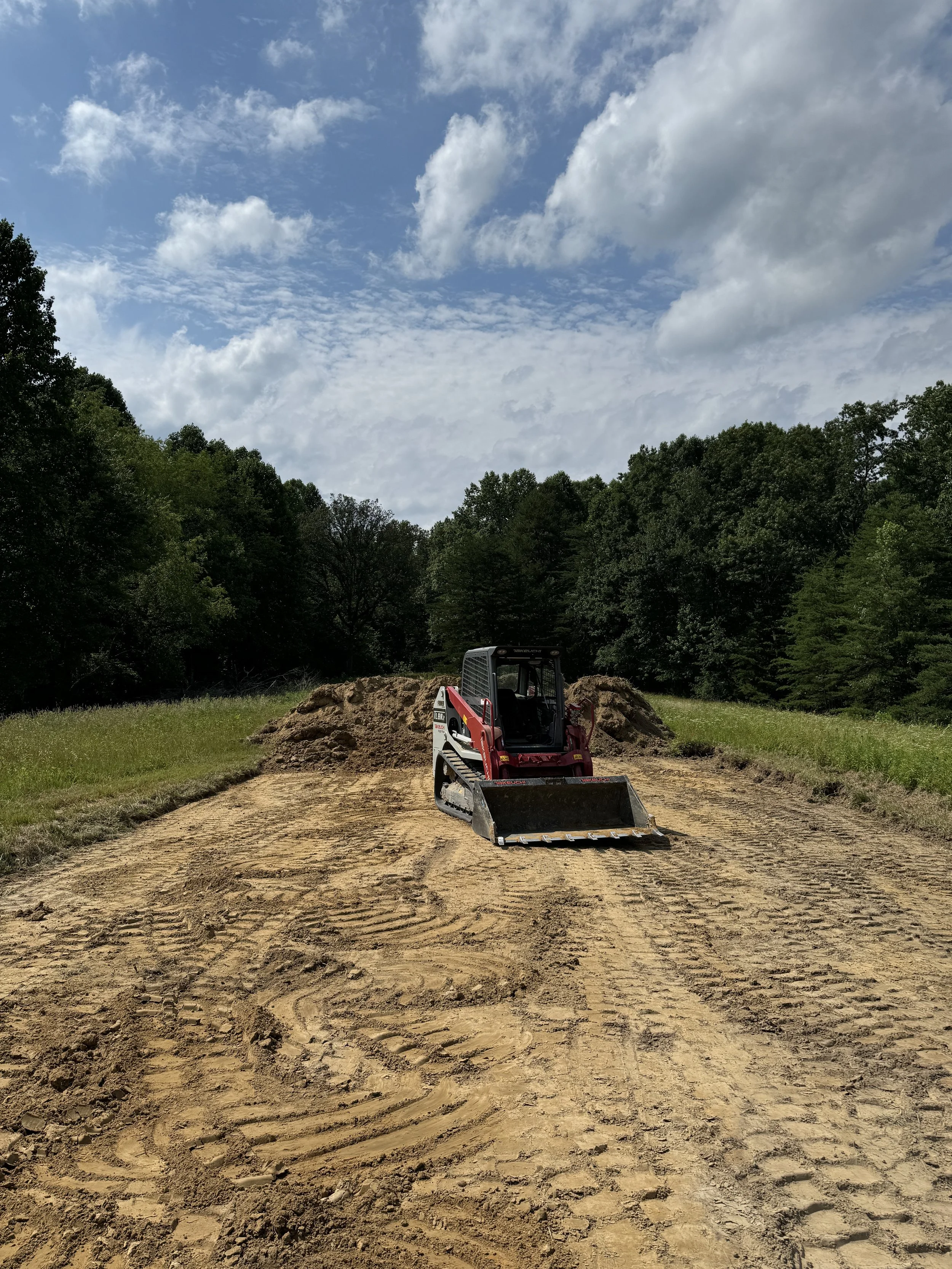  skid steer grading a wooded home site with fresh dirt work in Kentucky 