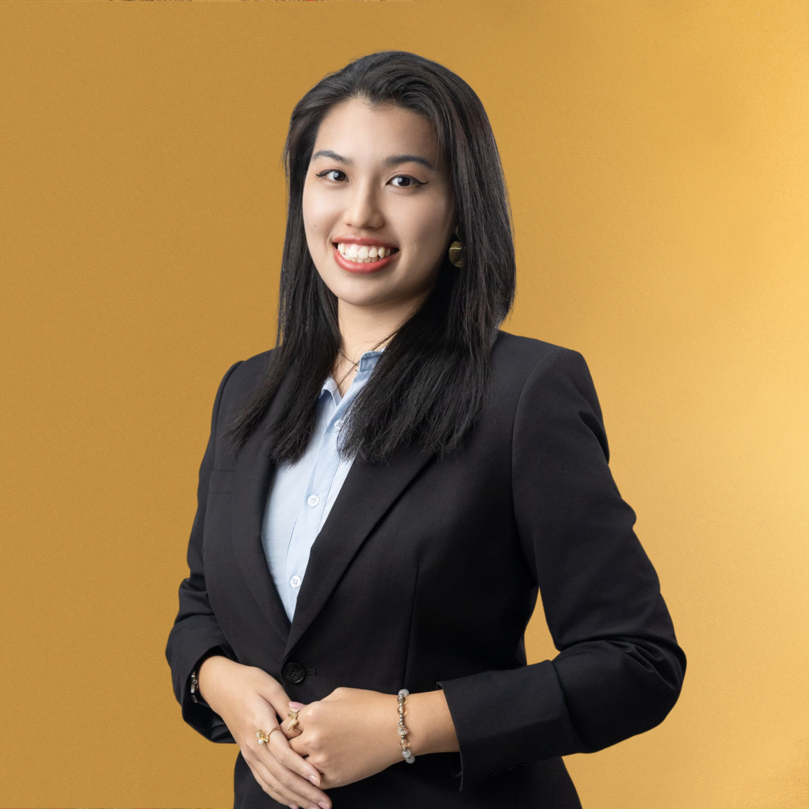 Young woman in business suit smiling against yellow background.