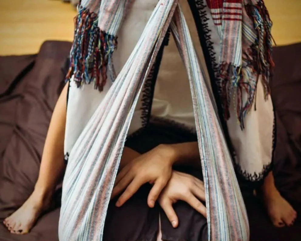 A modern house on a grassy hill with snow-capped mountains in the background under a cloudy sky.
