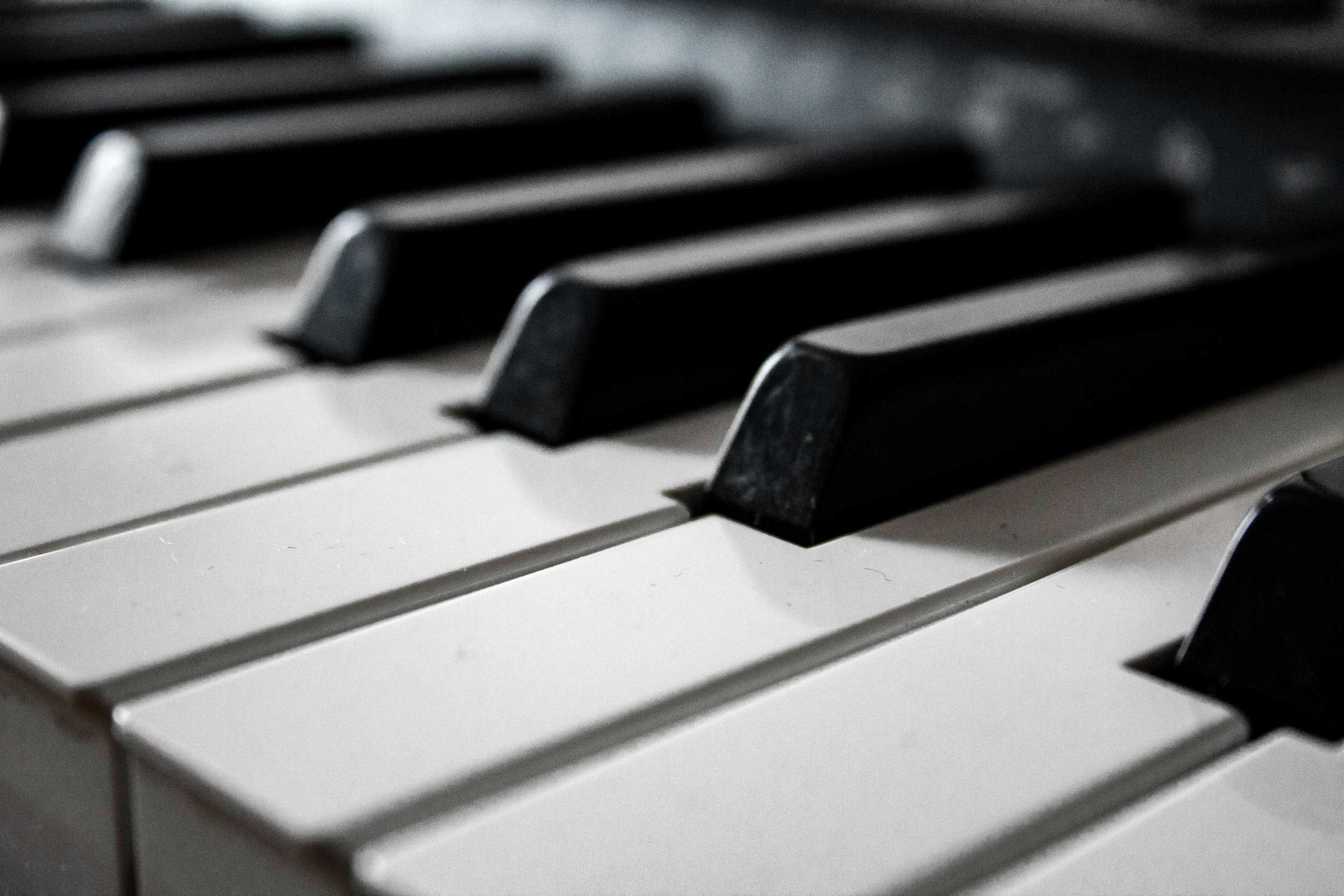 Close-up of black and white piano keys, showing some black keys and white keys promoting piano lessons.