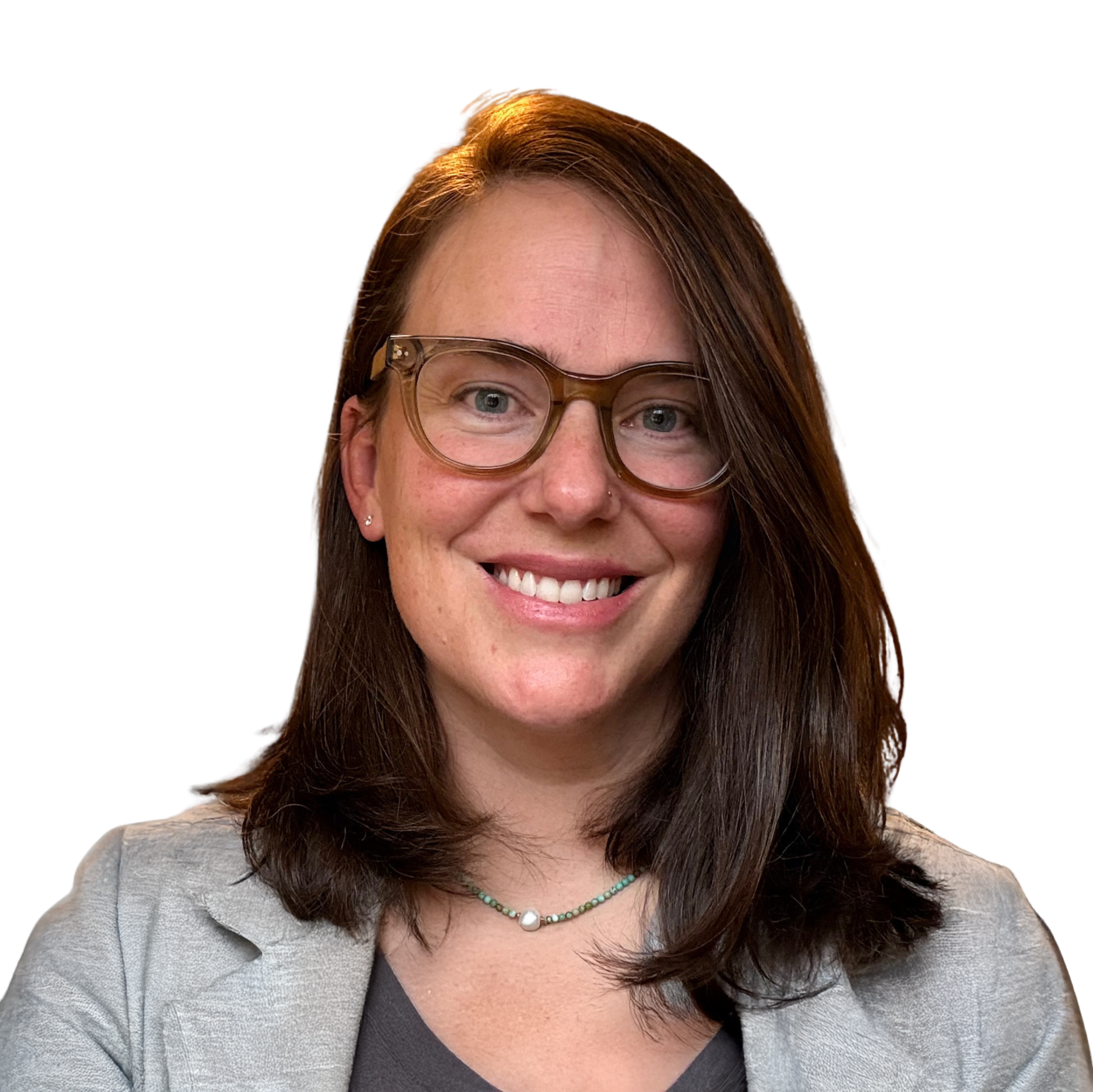 A smiling woman with shoulder-length brown hair, wearing glasses, a gray zip-up hoodie, and a beaded necklace, against a black background.