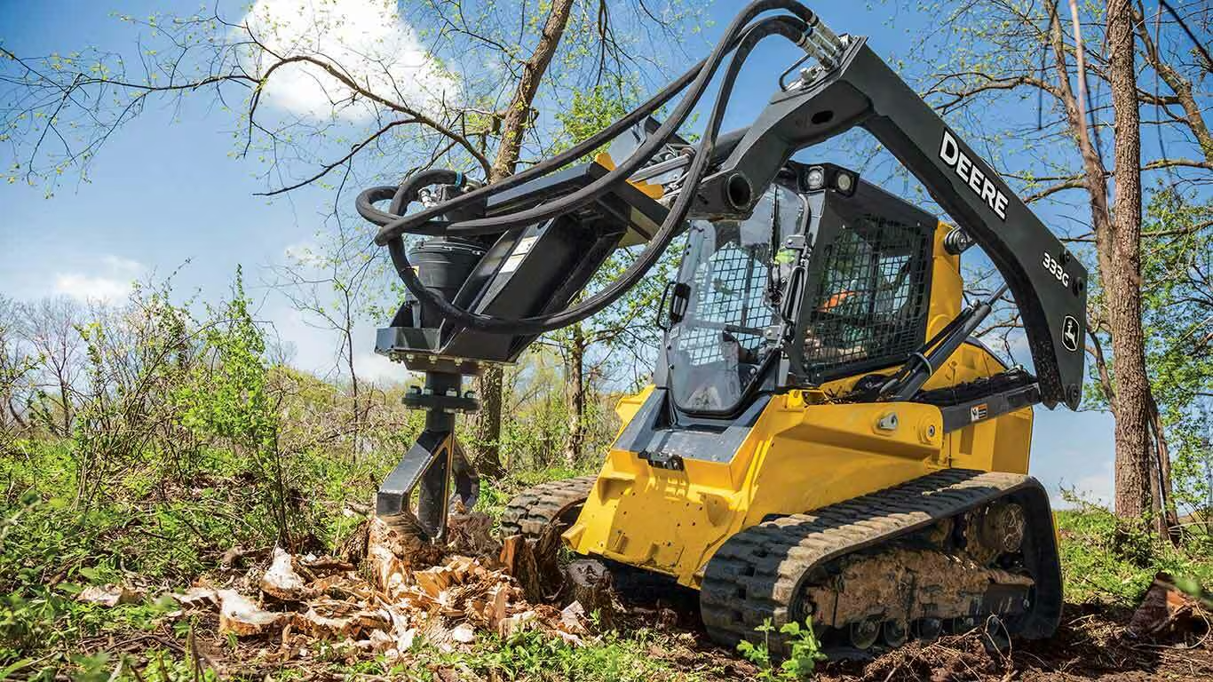 Compact track loader using a high-powered stump grinding shredder attachment to remove a tree stump quickly and efficiently.