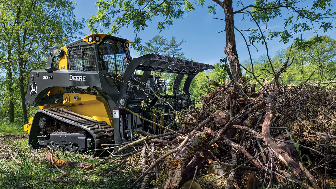 Skid steer removing brush and debris during a land clearing and brush cleanup project.