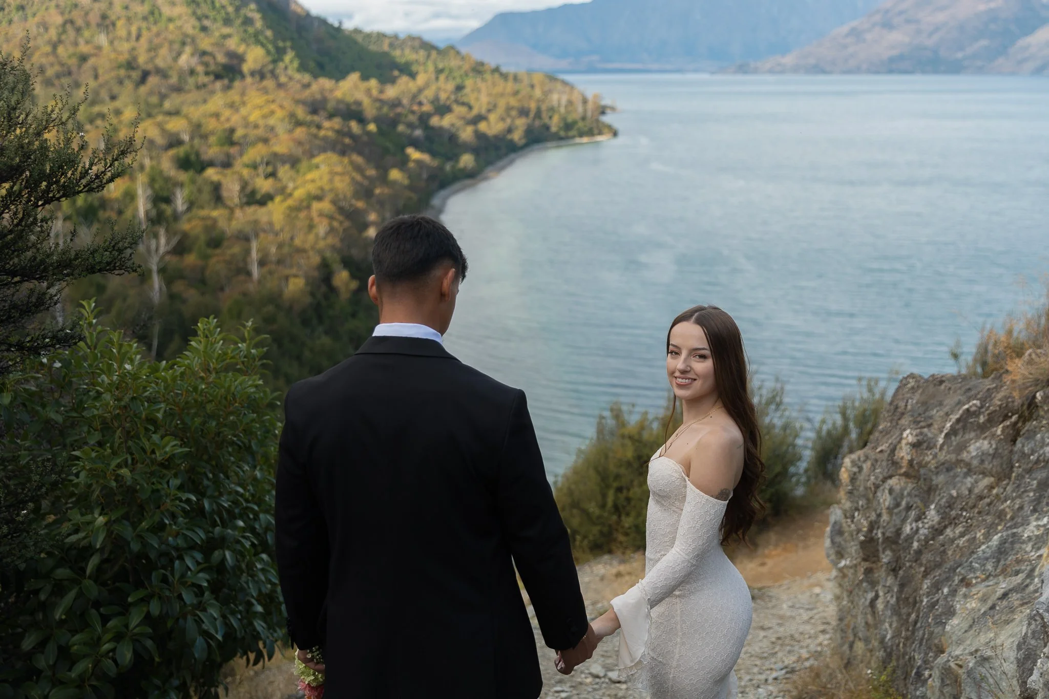 Couple holding hands on their elopement at the walking track Bobs Cove Queenstown