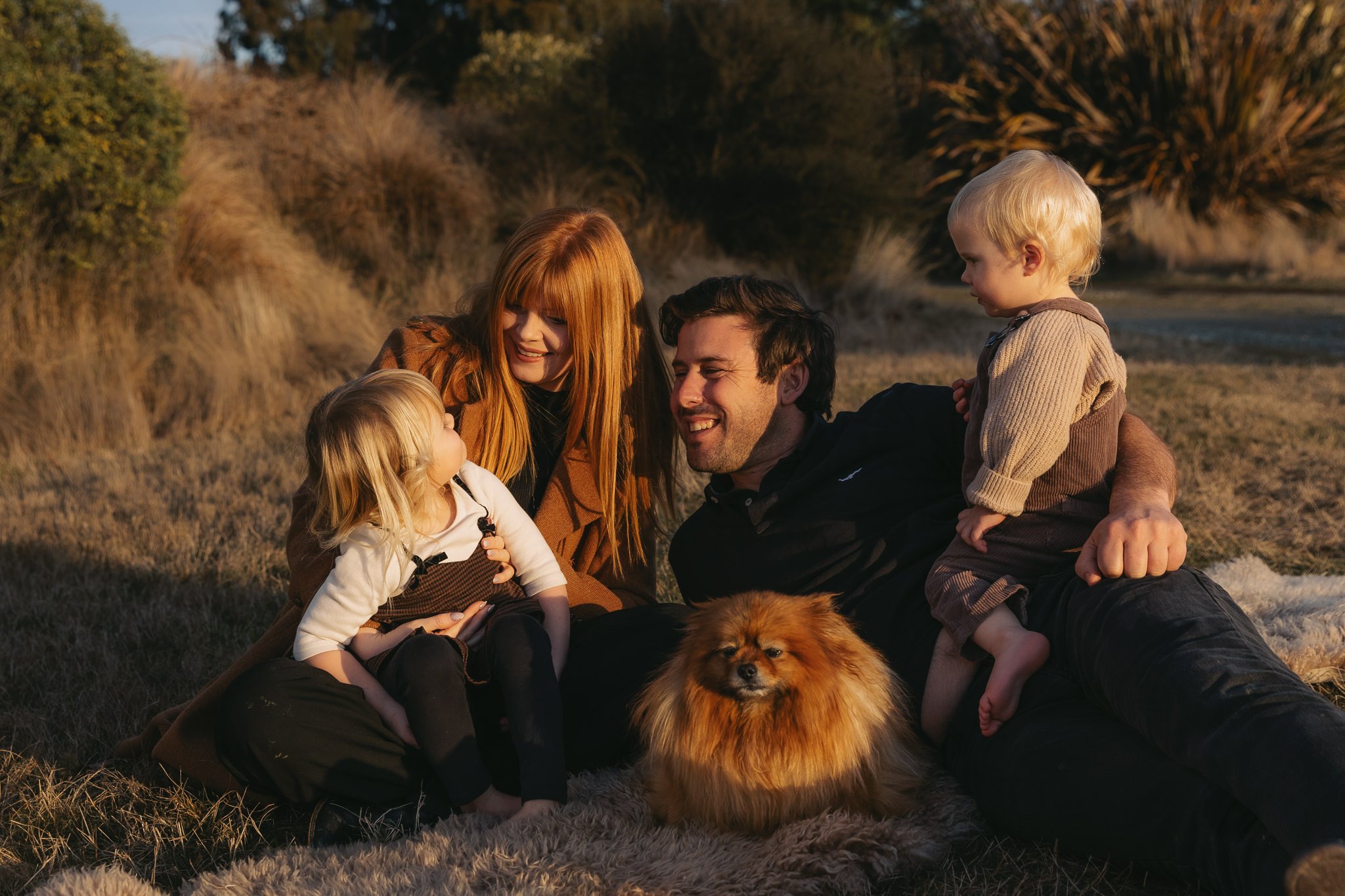 Family of four lying on the ground at sunset connecting. Wanaka New Zealand