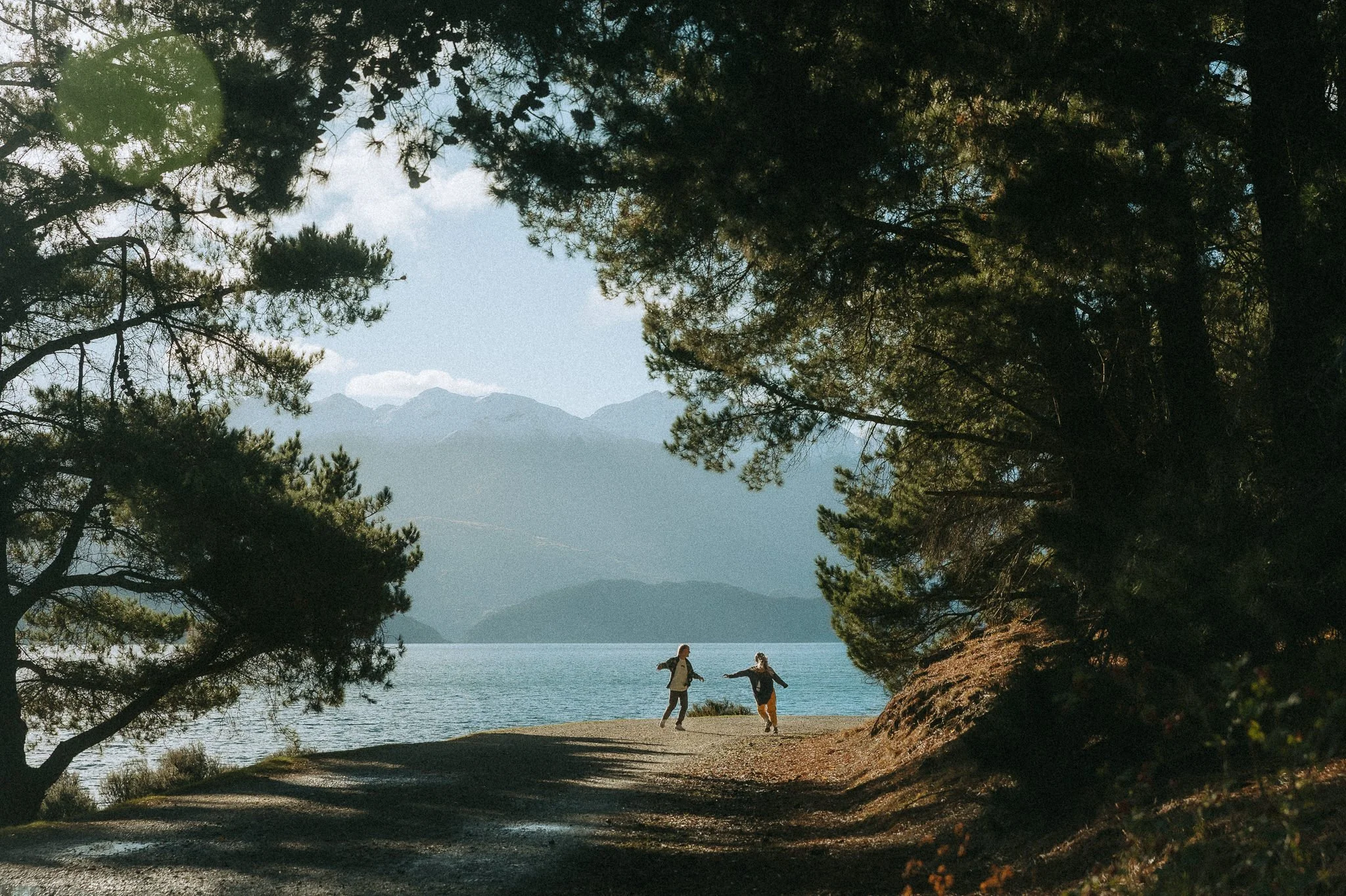 Couple running around playing below the mountains at eely point Wanaka New Zealand.