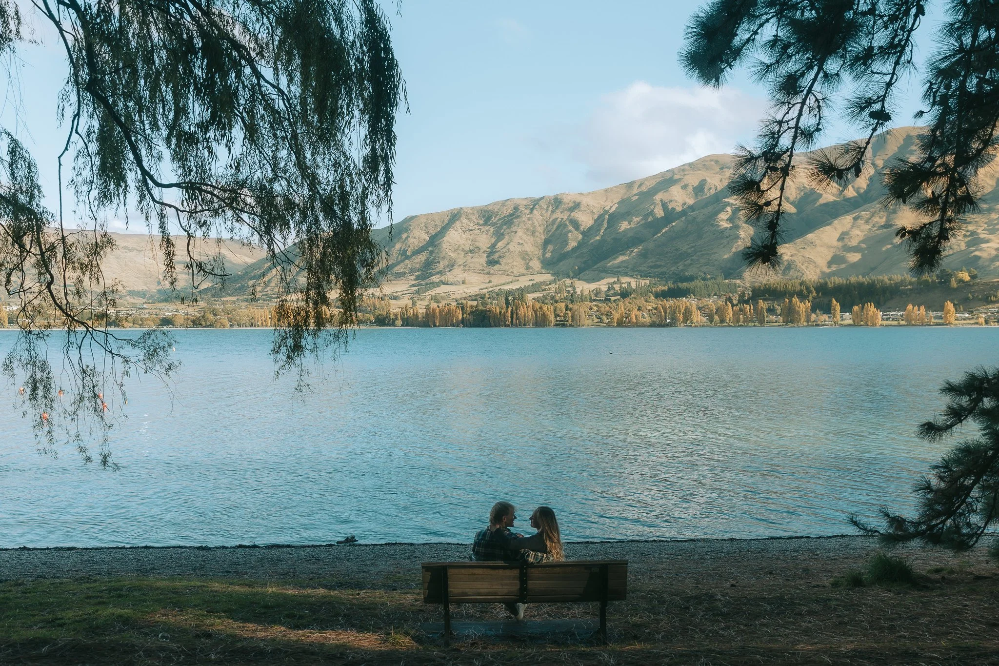 Couple sit on bench looking over lake wanaka.