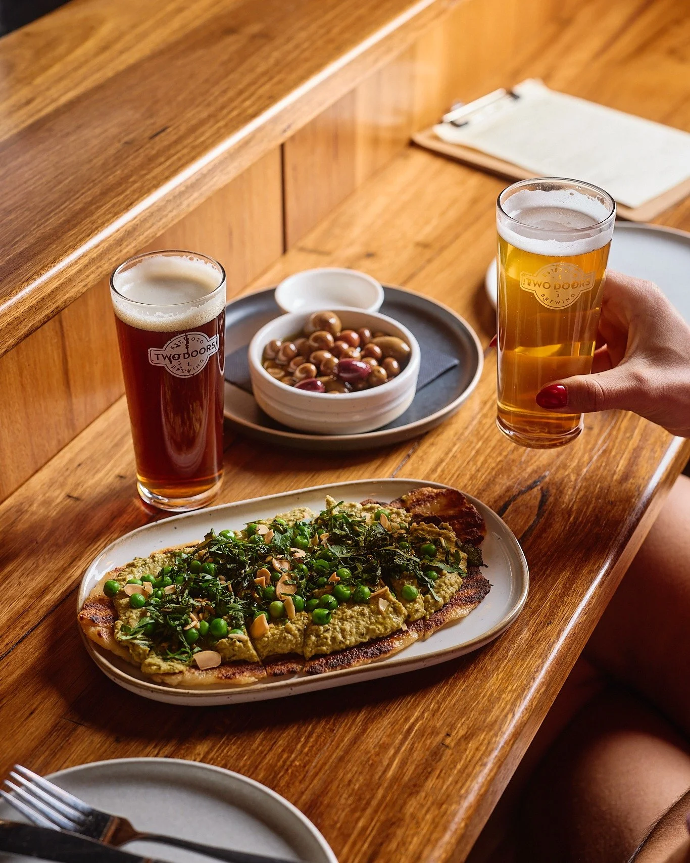 Our house-made yoghurt flatbread topped with pea hummus, almond, mint, and fresh peas, is the perfect snack to pair with a beer. Fresh, vibrant, and made to share, it&rsquo;s the ideal companion for your next brewery visit.