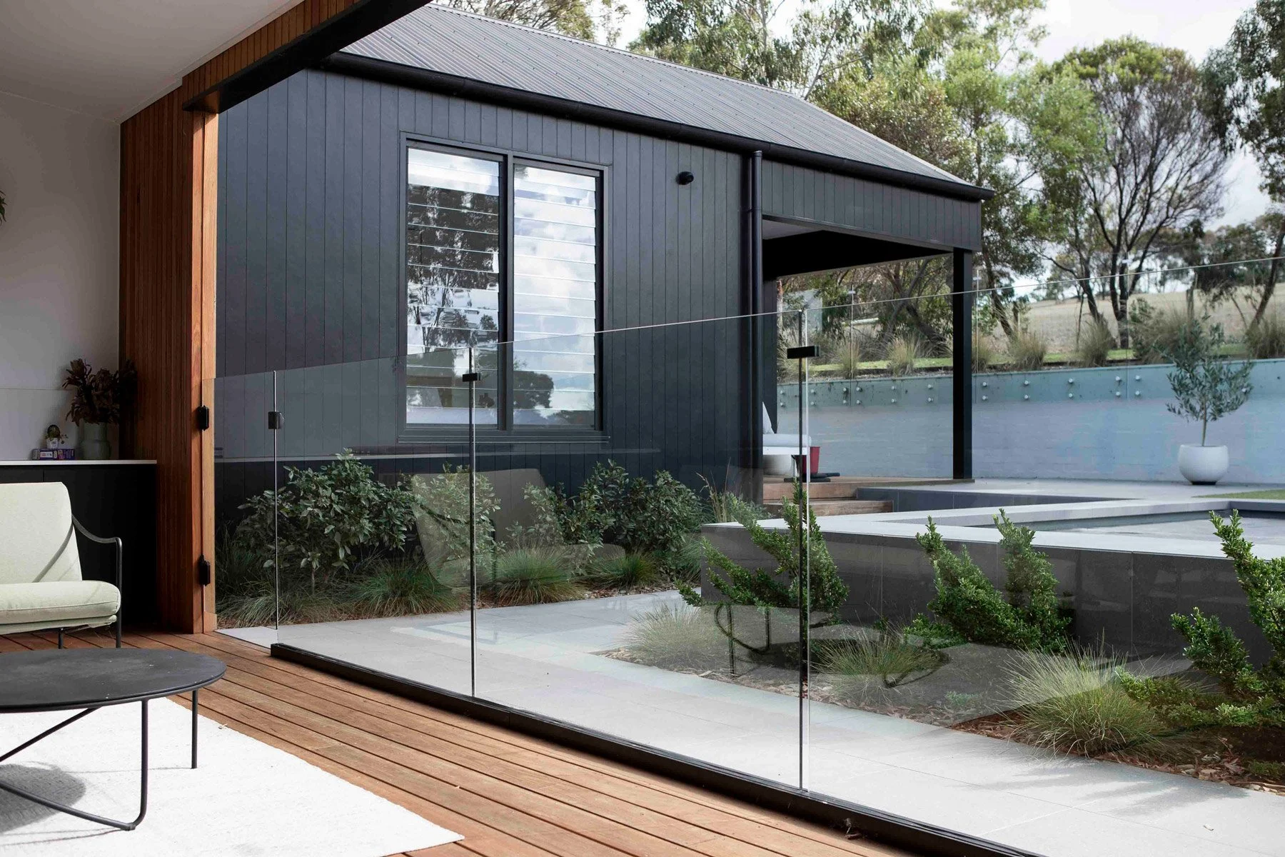 Residential window cleaning Surf Coast — modern black home with large glass balustrade panels and timber deck