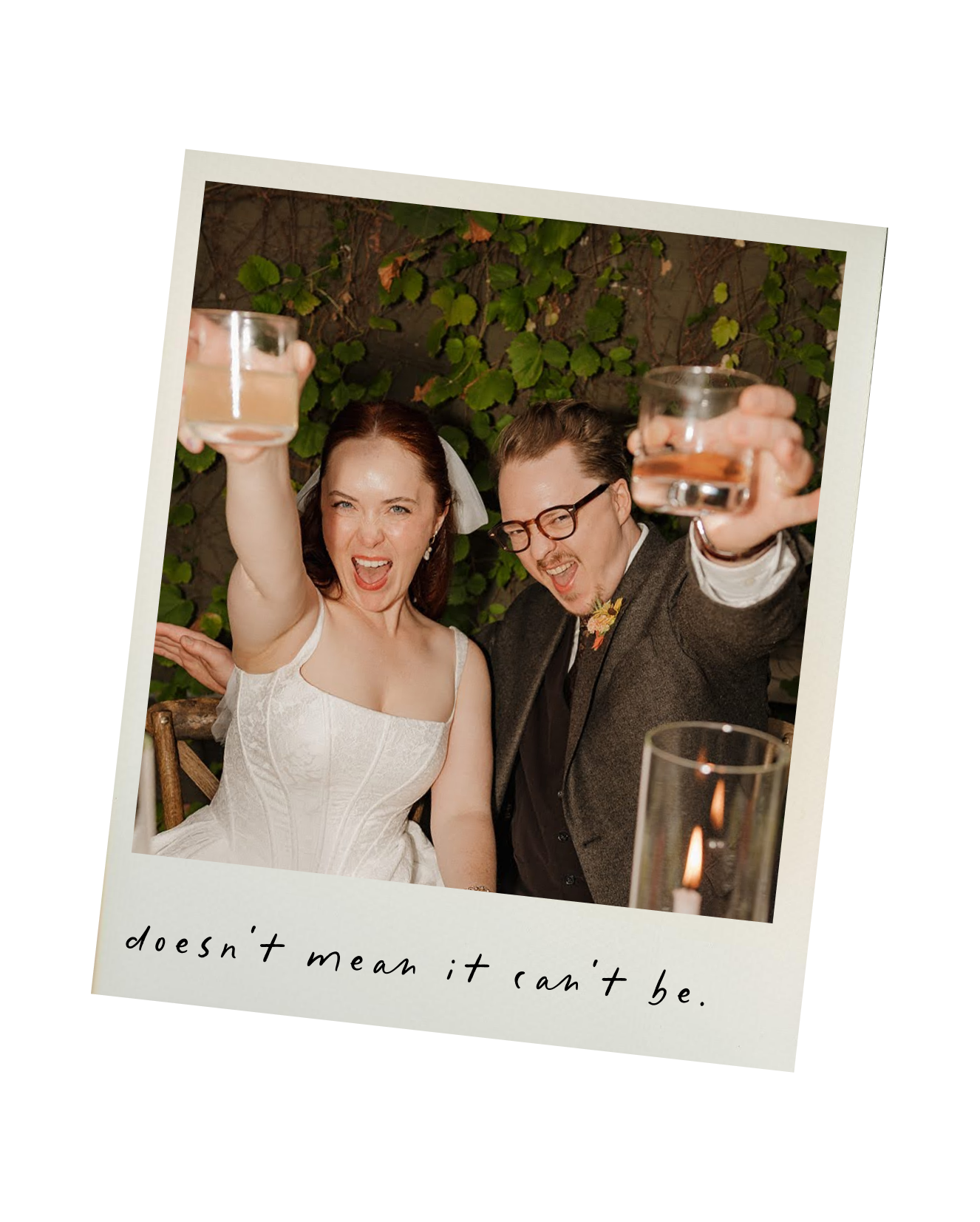 A woman in a white wedding dress and a man in glasses and a suit are celebrating with drinks, smiling and raising glasses in a toast, outdoors with green foliage background. The photo has a caption that says 'doesn't mean it can't be.'