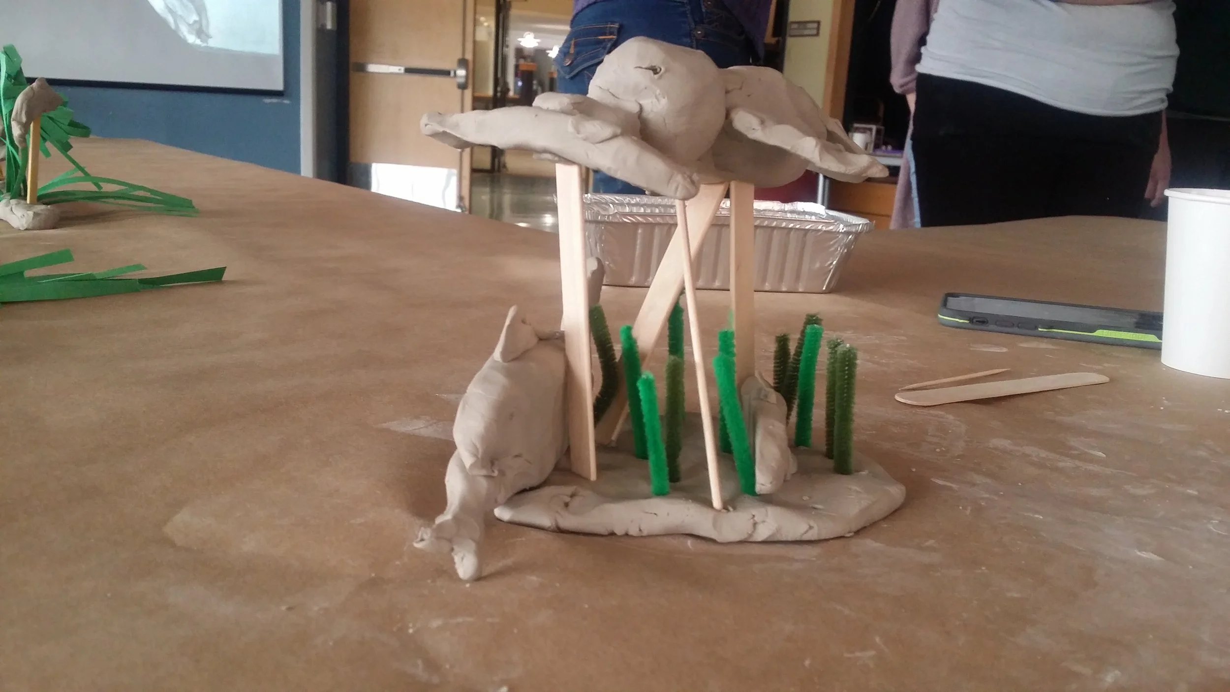 a clay based sculpture of someone's research. it has fish and a bird carrying a fish away
