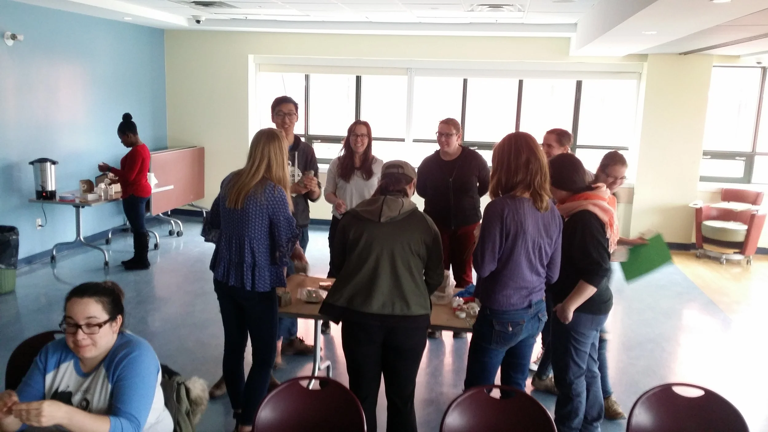 a group stands around a table. most are not facing the camera