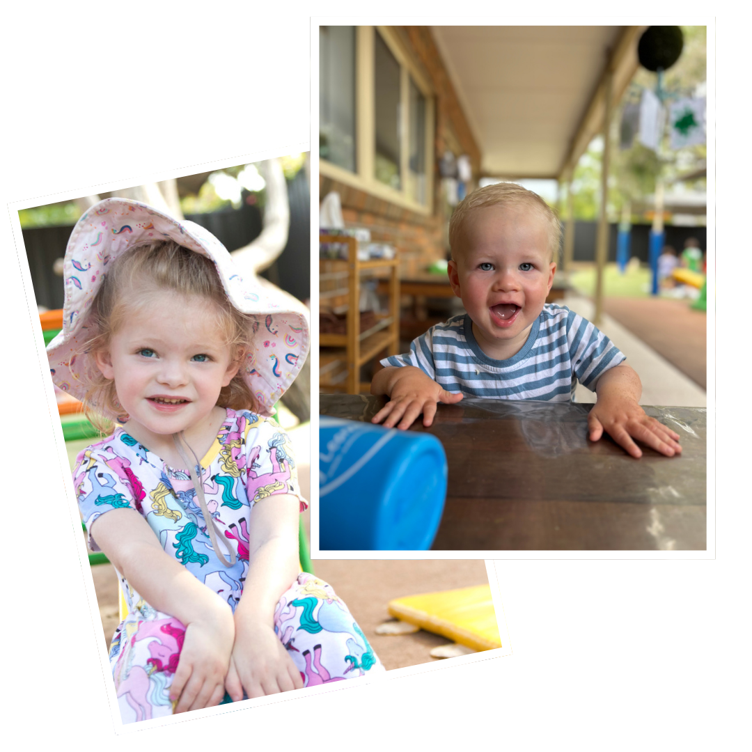 Two children, a girl and a boy, outdoors. The girl is wearing a colorful unicorn dress and a sun hat, smiling at the camera. The boy is sitting at a table, wearing a striped shirt, and looking at the camera with his mouth open.