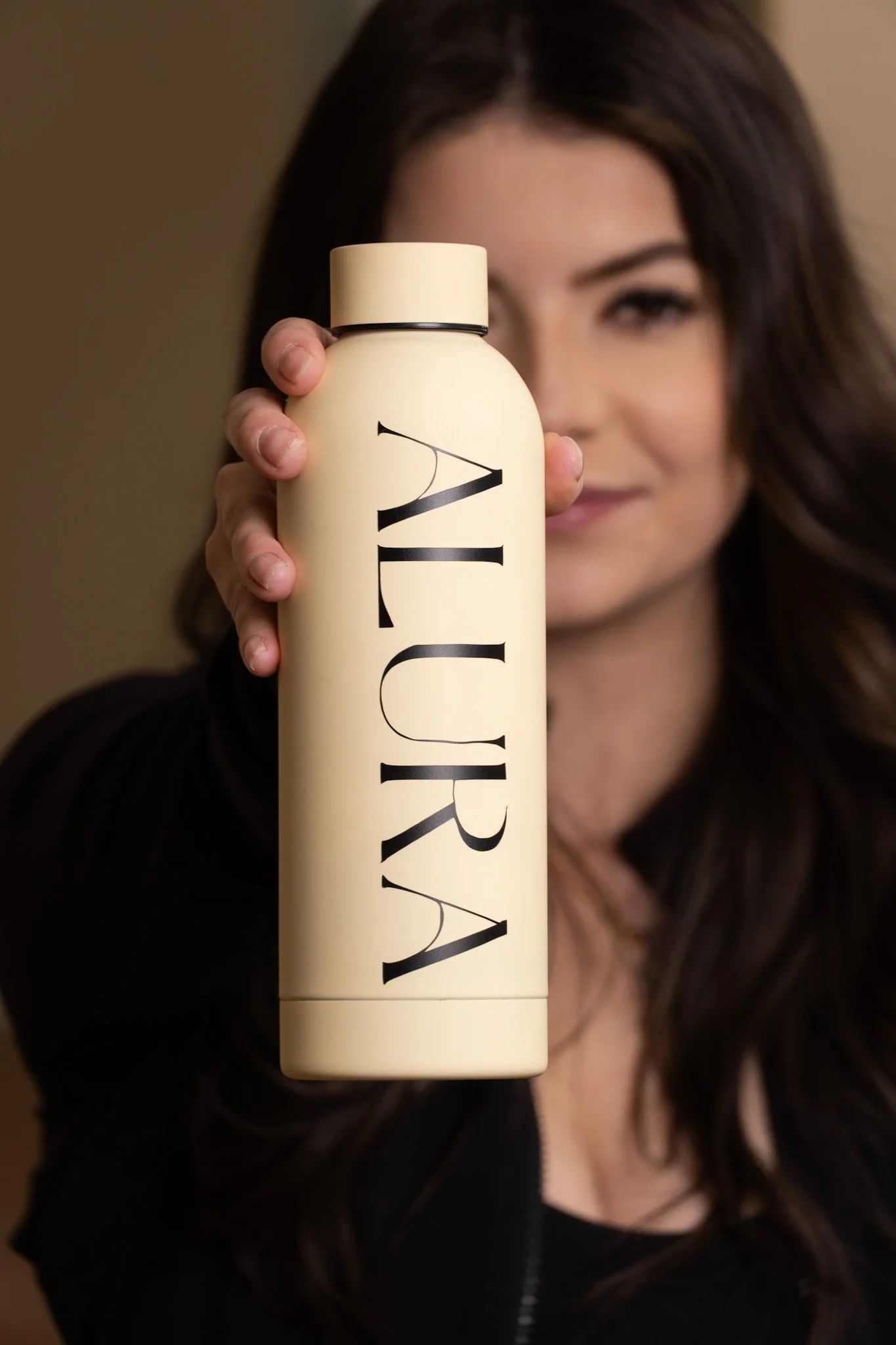 Owner of ALURA  holding a business branded water bottle.