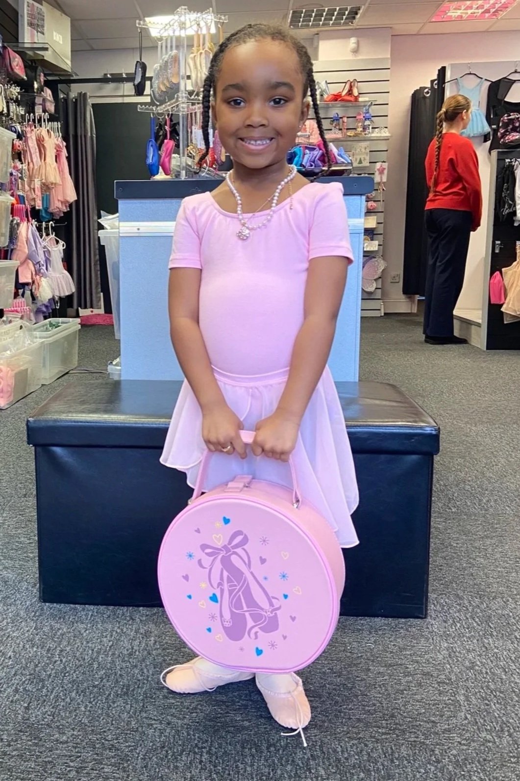 Dancer from Castle Street Dance studios in her new ballet uniform of pink ballet leotard, pink ballet skirt, ballet shoes and ballet socks. She is holding her new ballet bag - a vanity case with ballet shoe print on it.