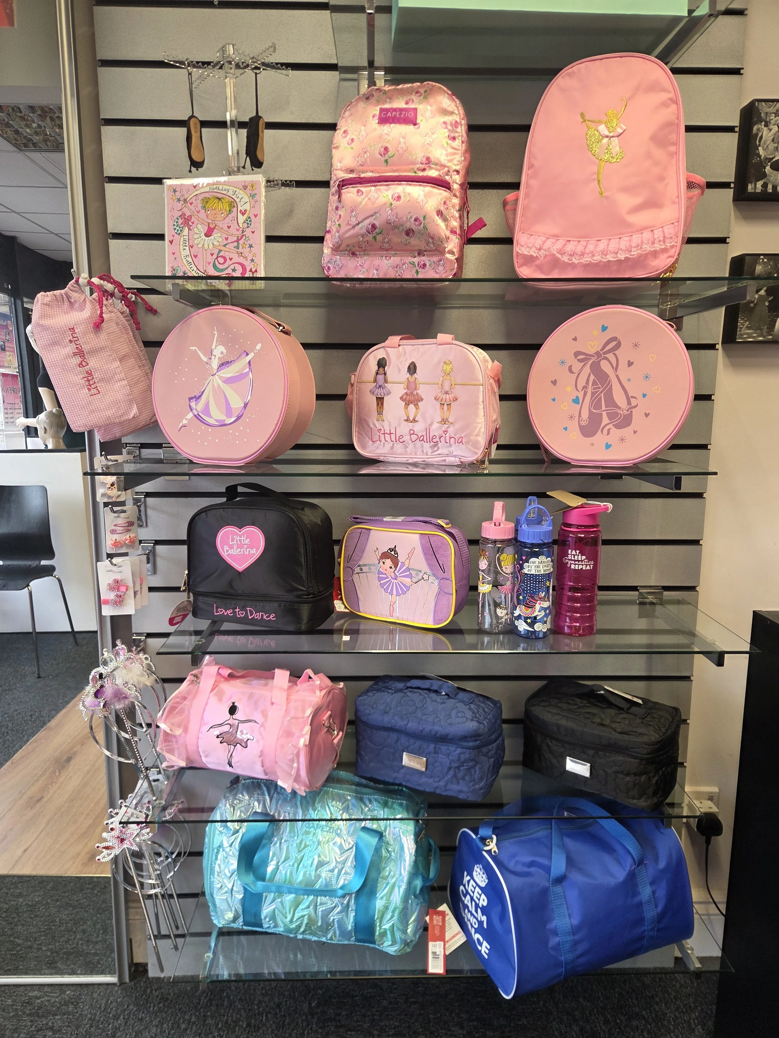 Six pink dance bags, two black dance bags and three blue dance bags. Also pictured are hair accessories, water bottles and tiaras.