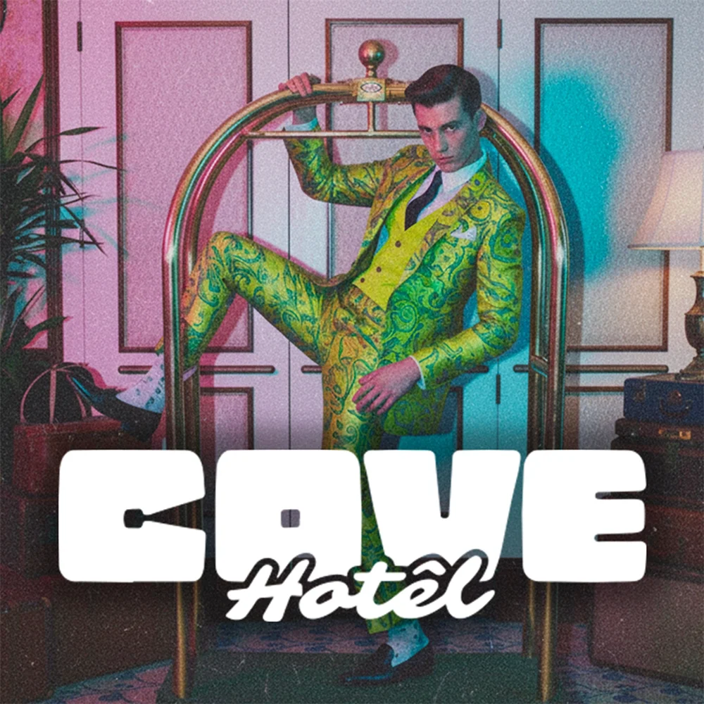 Un homme en costume jaune à motifs verts pose dans une pièce avec un mobilier rétro. Il se tient dans une station de métro avec un arc en or. Le texte "CAVE hotel" est affiché en bas de l'image.