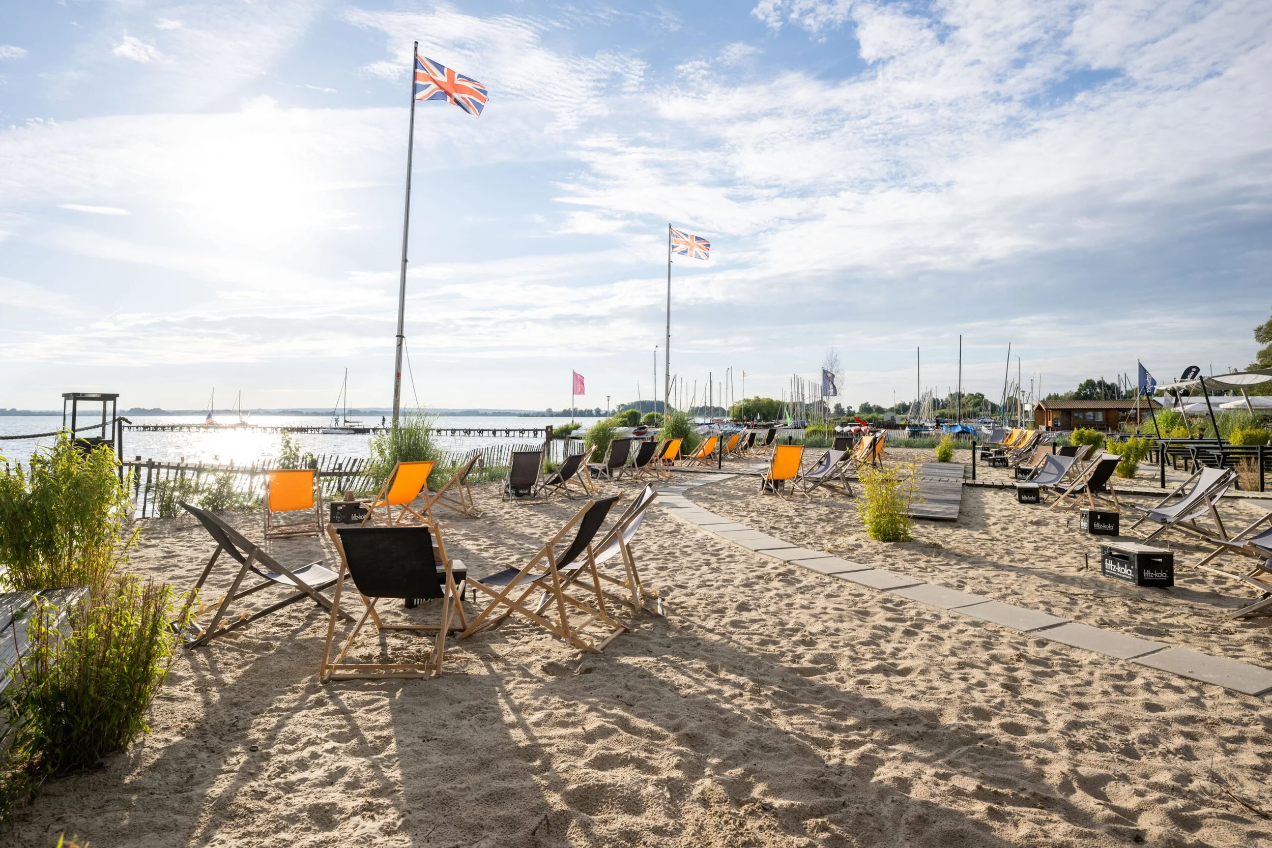 Leerer Strand mit Liegestühlen, Flaggen, Wasser und Himmel
