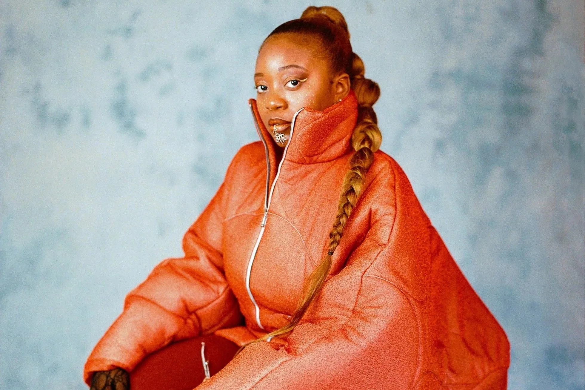 Portrait d'une femme portant une veste orange avec une longue tresse.