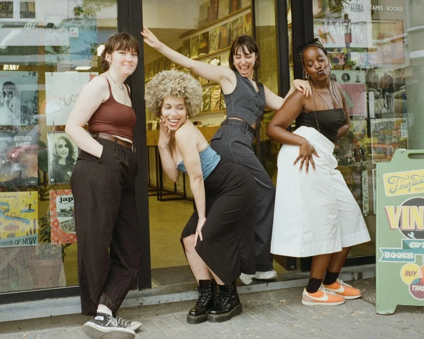 Quatre femmes posent de manière expressive devant une vitrine de librairie, montrant leur personnalité et diversité.