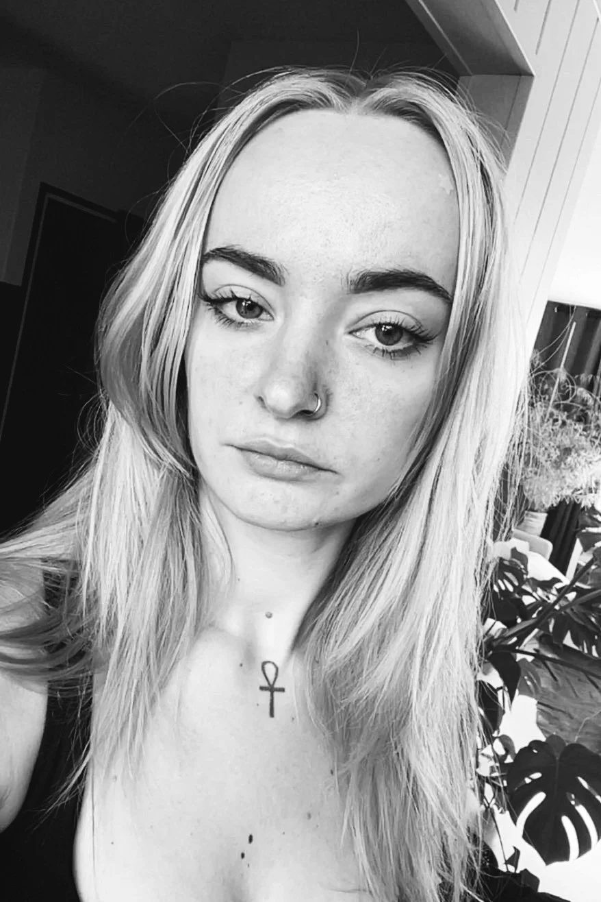 Black and white photo of a young woman with long, blond hair, light eyes, and a nose ring.