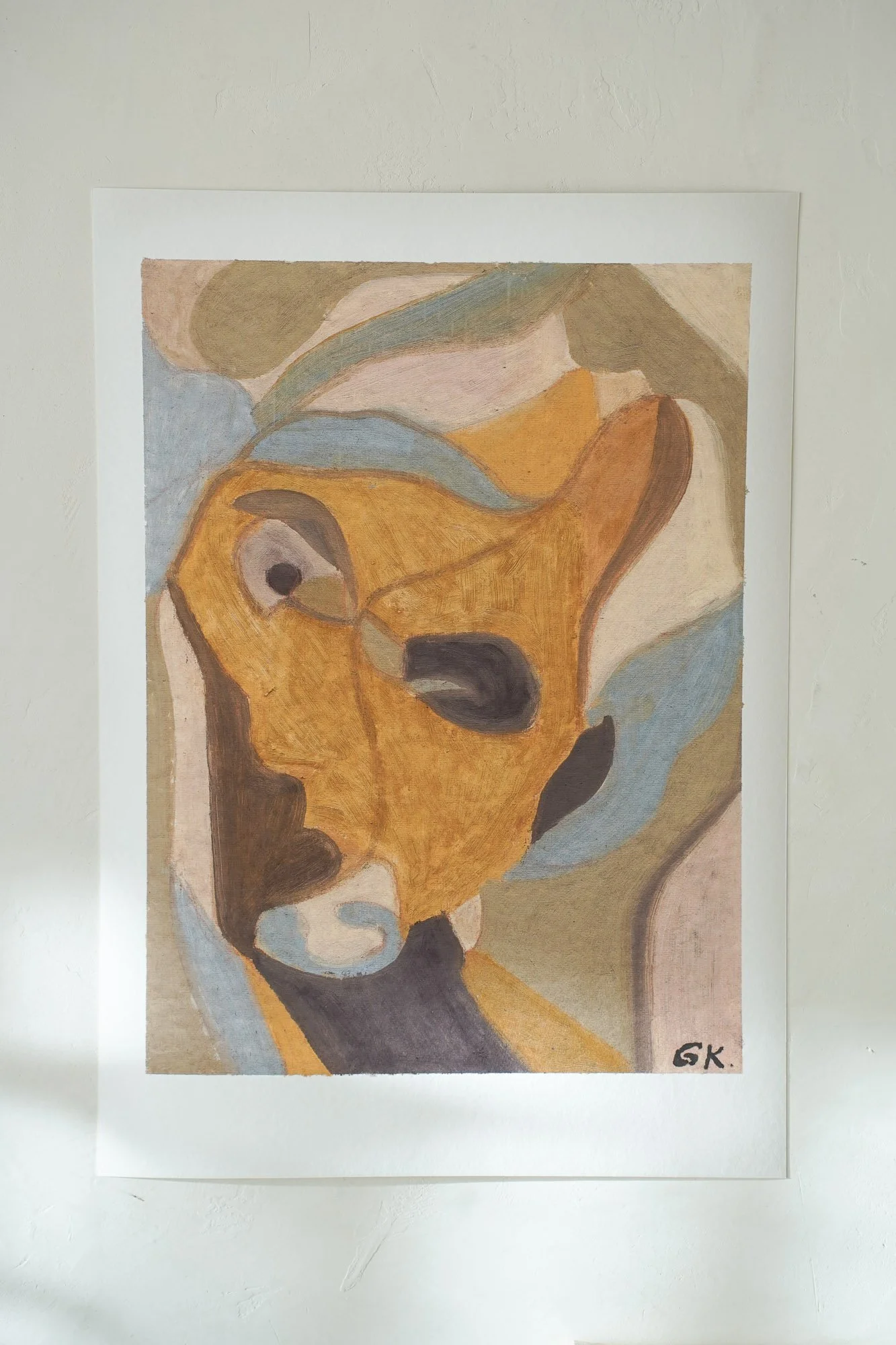 A figurative abstract painting of a goat with a focus on its face, using warm, earthy tones of yellow ochre, brown, and black, with some blue and beige accents.