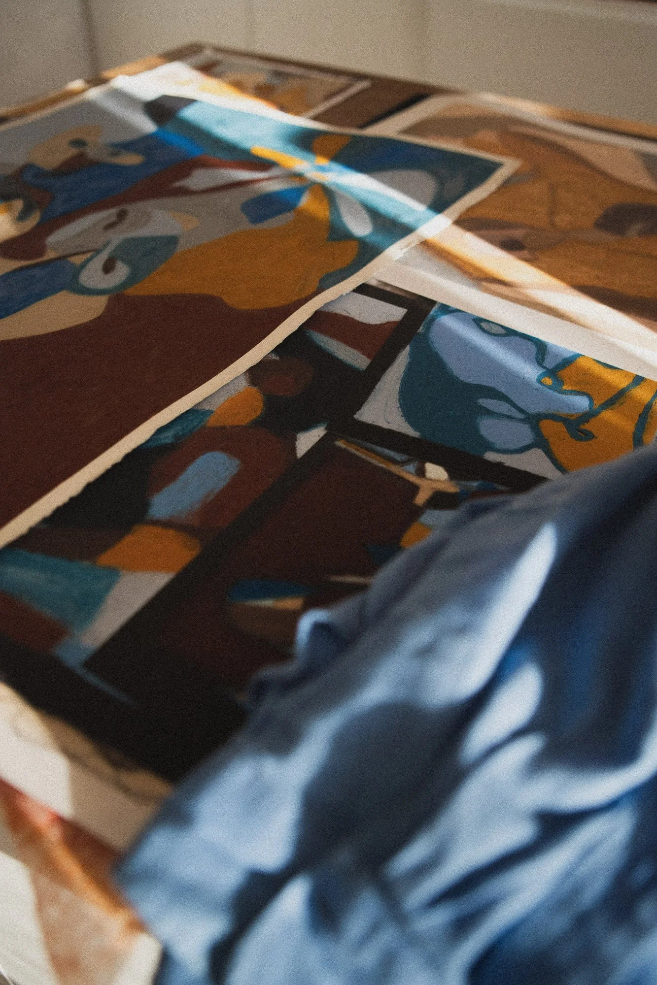 Multiple colorful abstract figurative paintings placed on a wooden surface in an art studio in Oslo.