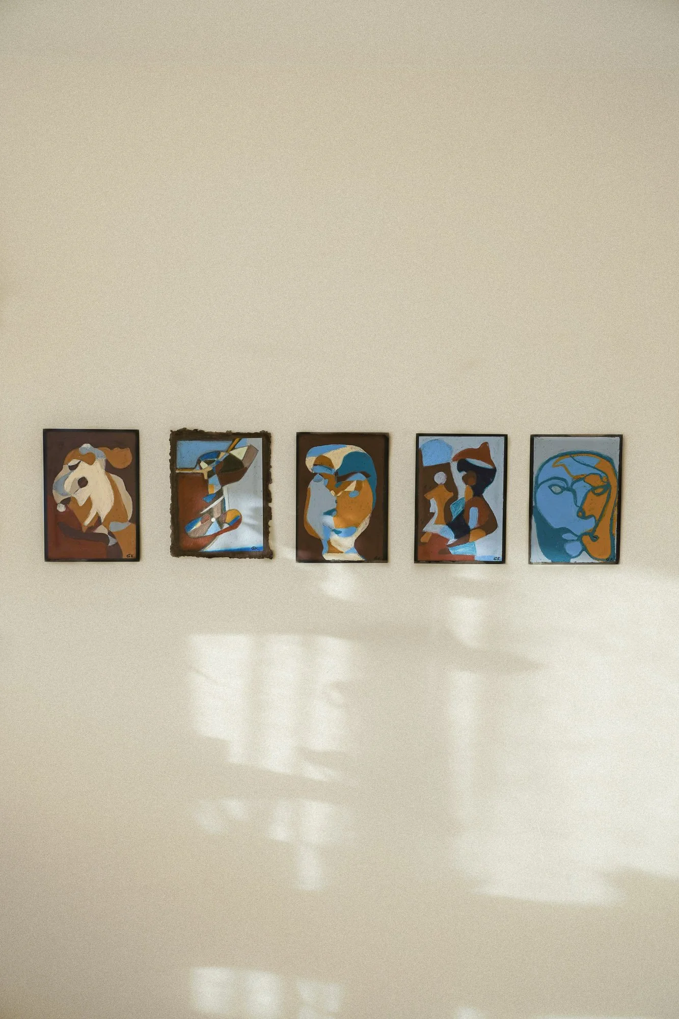 Five Cubist-style, abstract paintings of human faces and figures hanging on a white gallery wall, in an art studio located in Oslo.