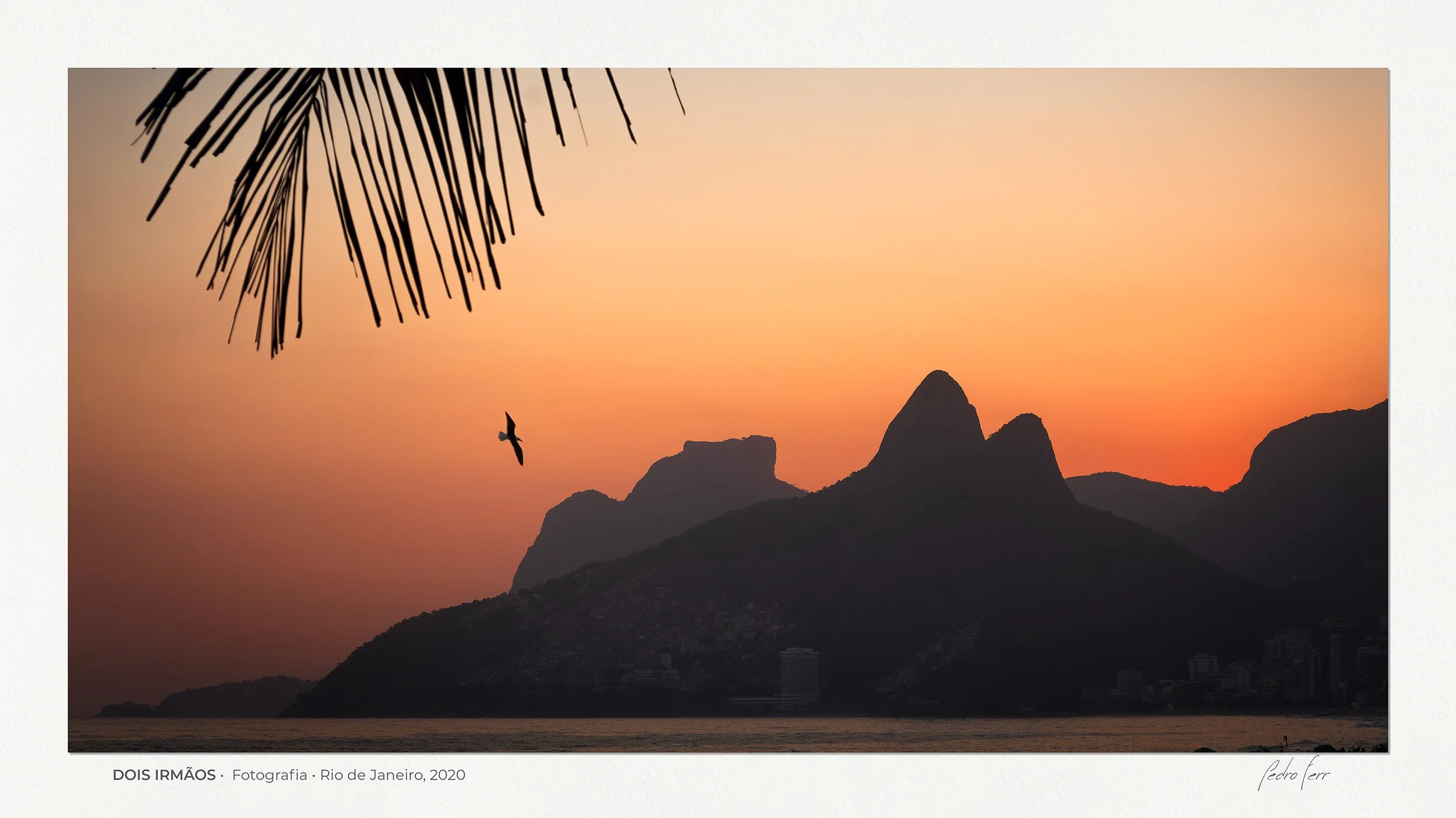Silhueta icônica do Morro Dois Irmãos recortada contra um céu de gradiente dourado e alaranjado, com detalhes sutis da cidade e folhas de palmeira em primeiro plano. Uma obra que captura a pulsação do Rio de Janeiro em harmonia com o silêncio do mar,