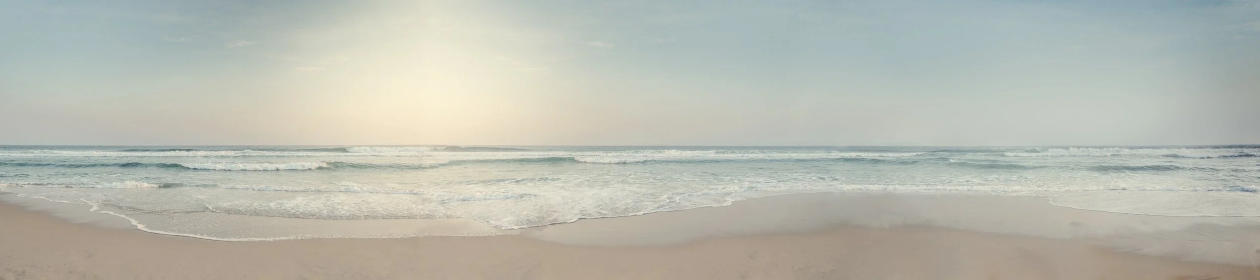 Vista panorâmica da praia no Rio de Janeiro com areia limpa, ondas tranquilas e horizonte amplo sob luz suave, ideal para projetos que pedem sensação de espaço, calma e neutralidade visual.