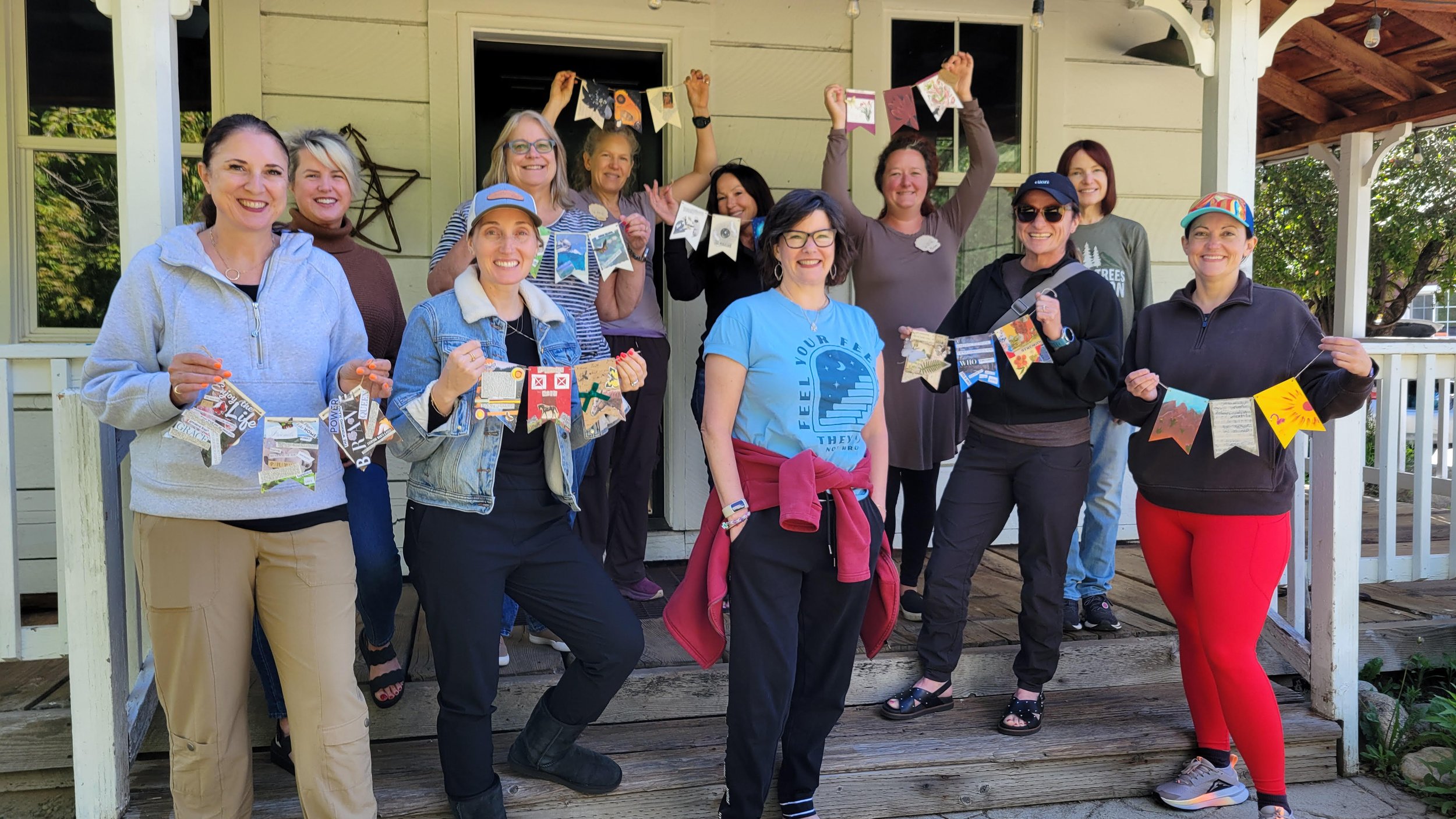 A group of women on the front porch of McBride House during Shine! 2026, holding their handmade banners.
