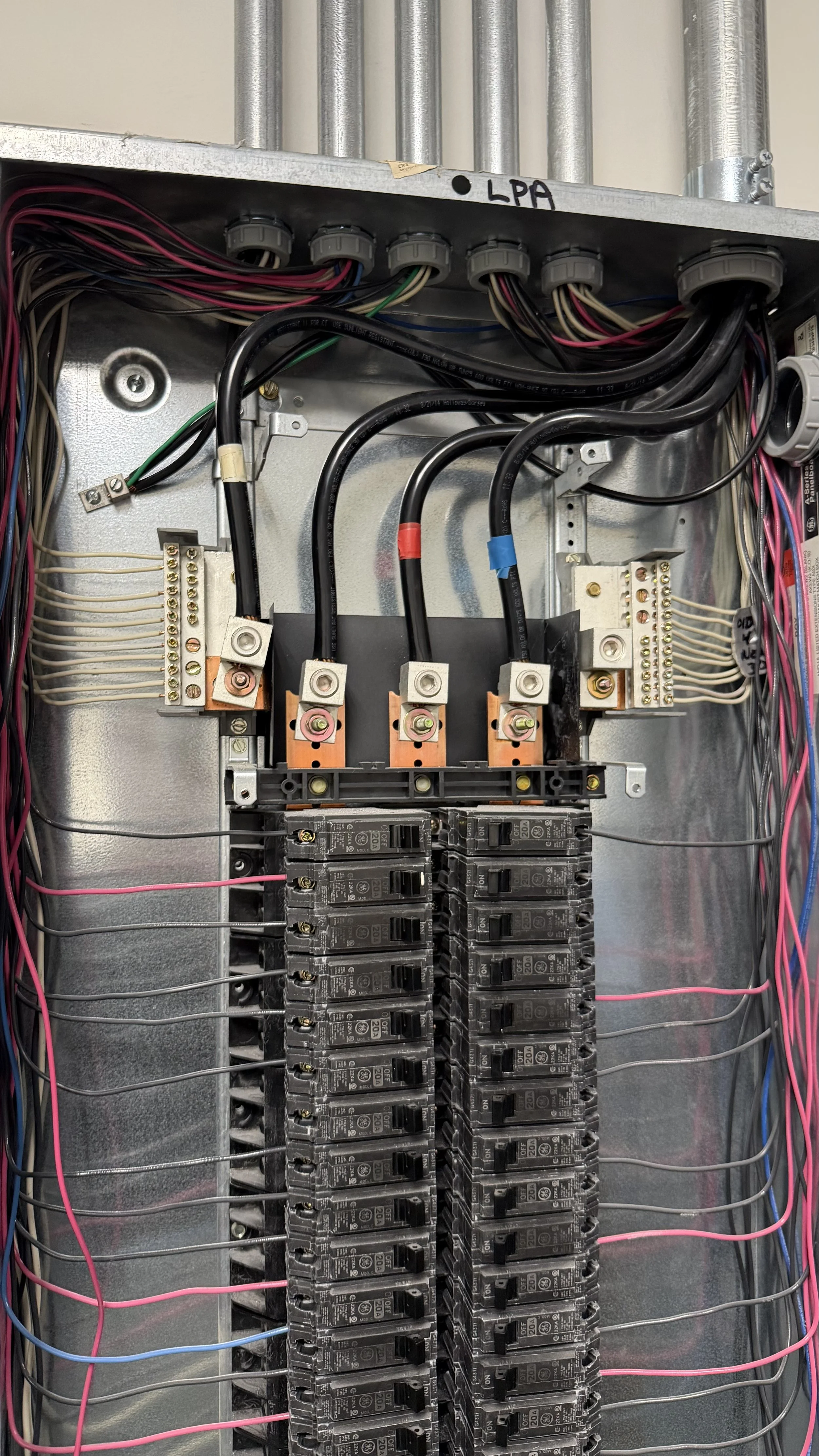 Indoor electrical panel with circuit breakers, wires, and bus bars.