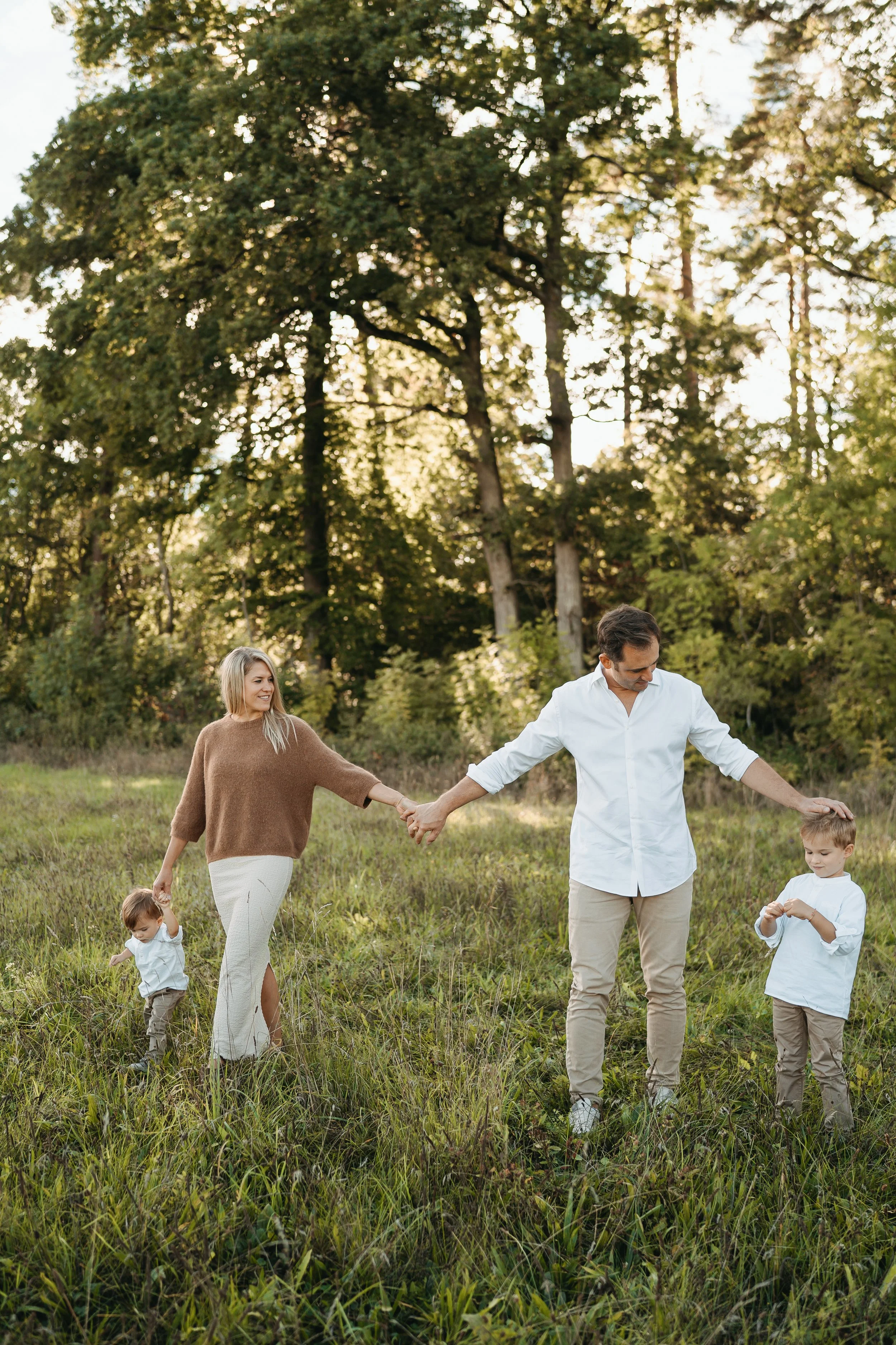 Familie mit zwei Kindern beim Spaziergang im Park an einem sonnigen Tag