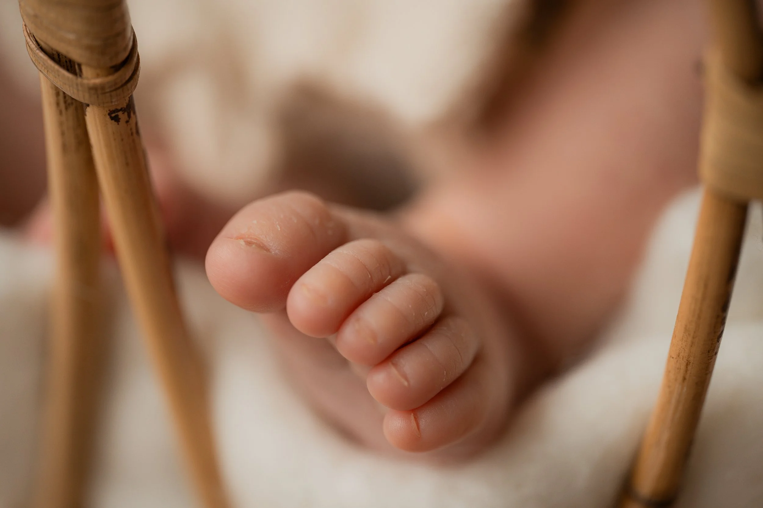 Nahaufnahme eines Babyfingers, der an einem Gitter hängt.